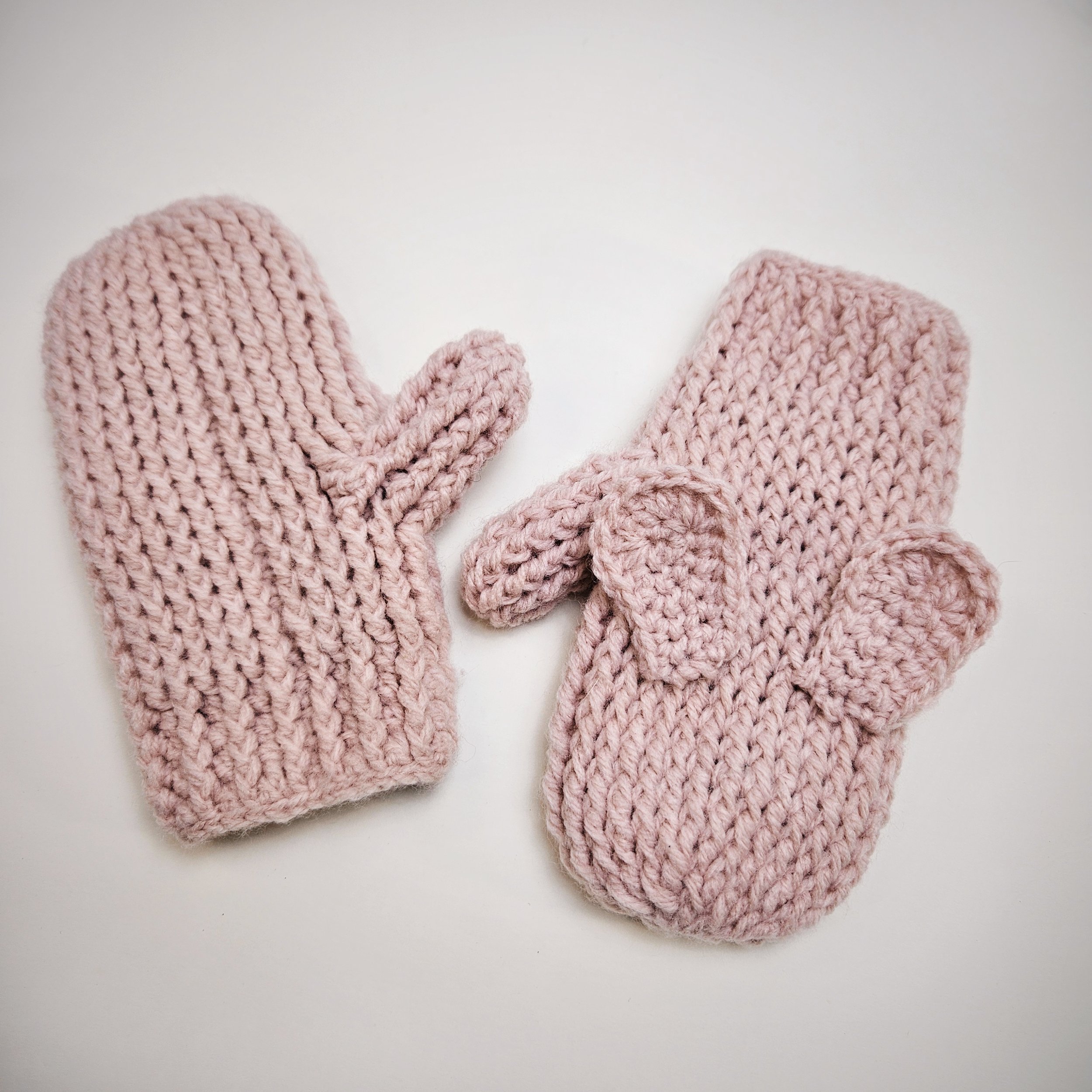 A pair of crochet bunny ear mittens laid flat, one showing the palm side and the other showing the back, highlighting the full design details.