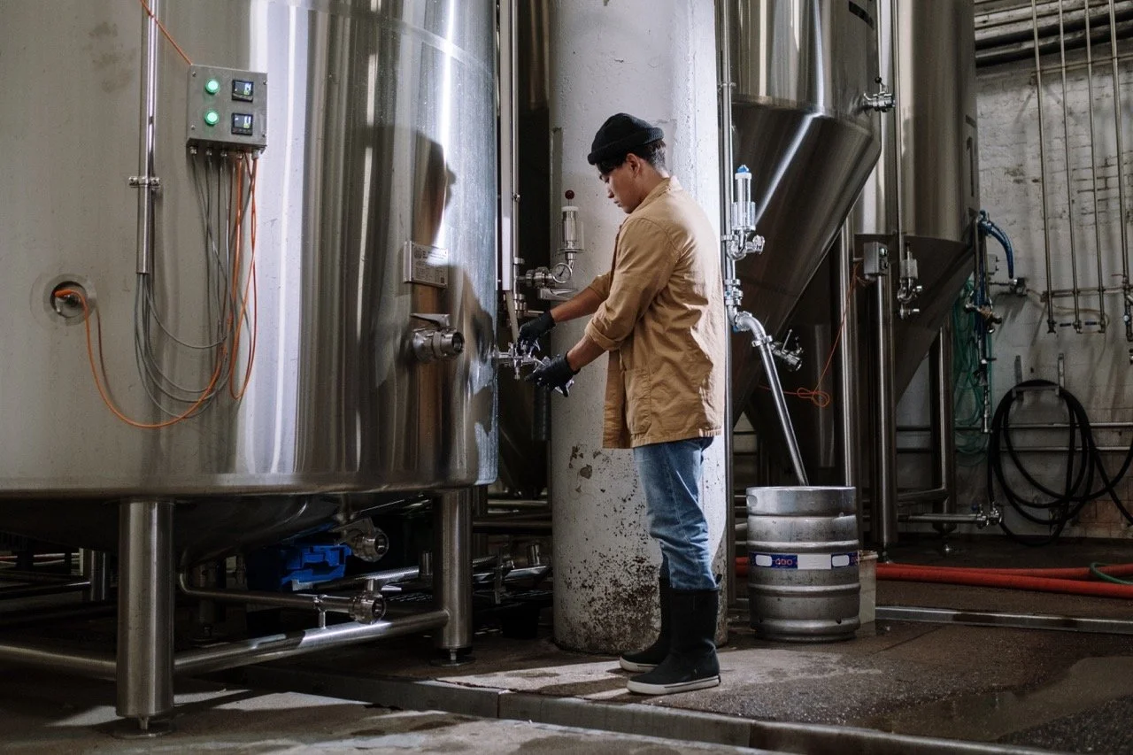 A man checking a cold brew batch in a tank, part of the process of crafting Black Geisha, a specialty cold brew coffee liqueur made with the illustrious Geisha coffee varietal.
