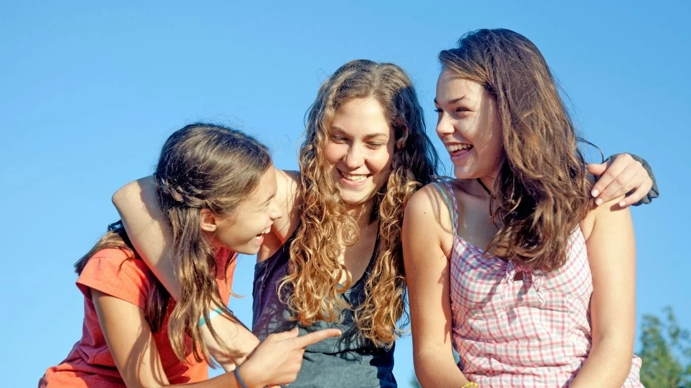 Group of adolescents sitting together outdoors and smiling.