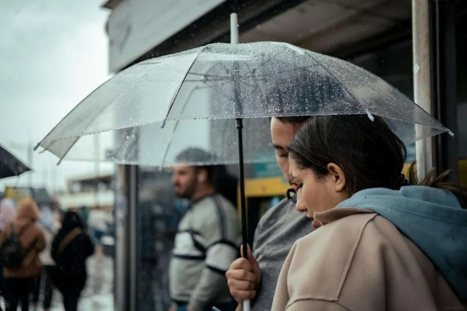 Couple sheltering together under an umbrella during a rainstorm