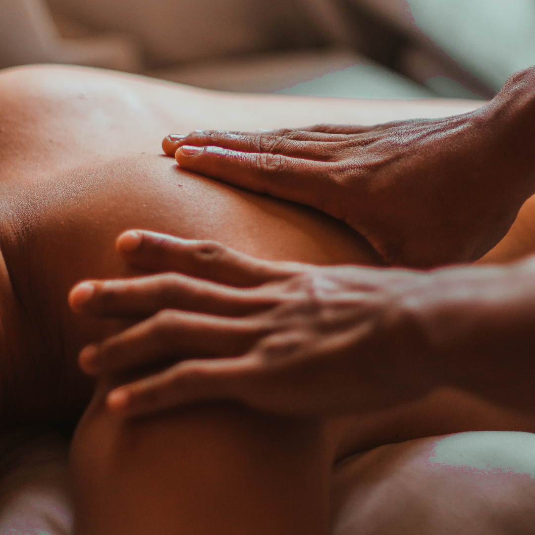 Close-up of a person receiving a massage, showing hands pressing on shoulder and back skin.