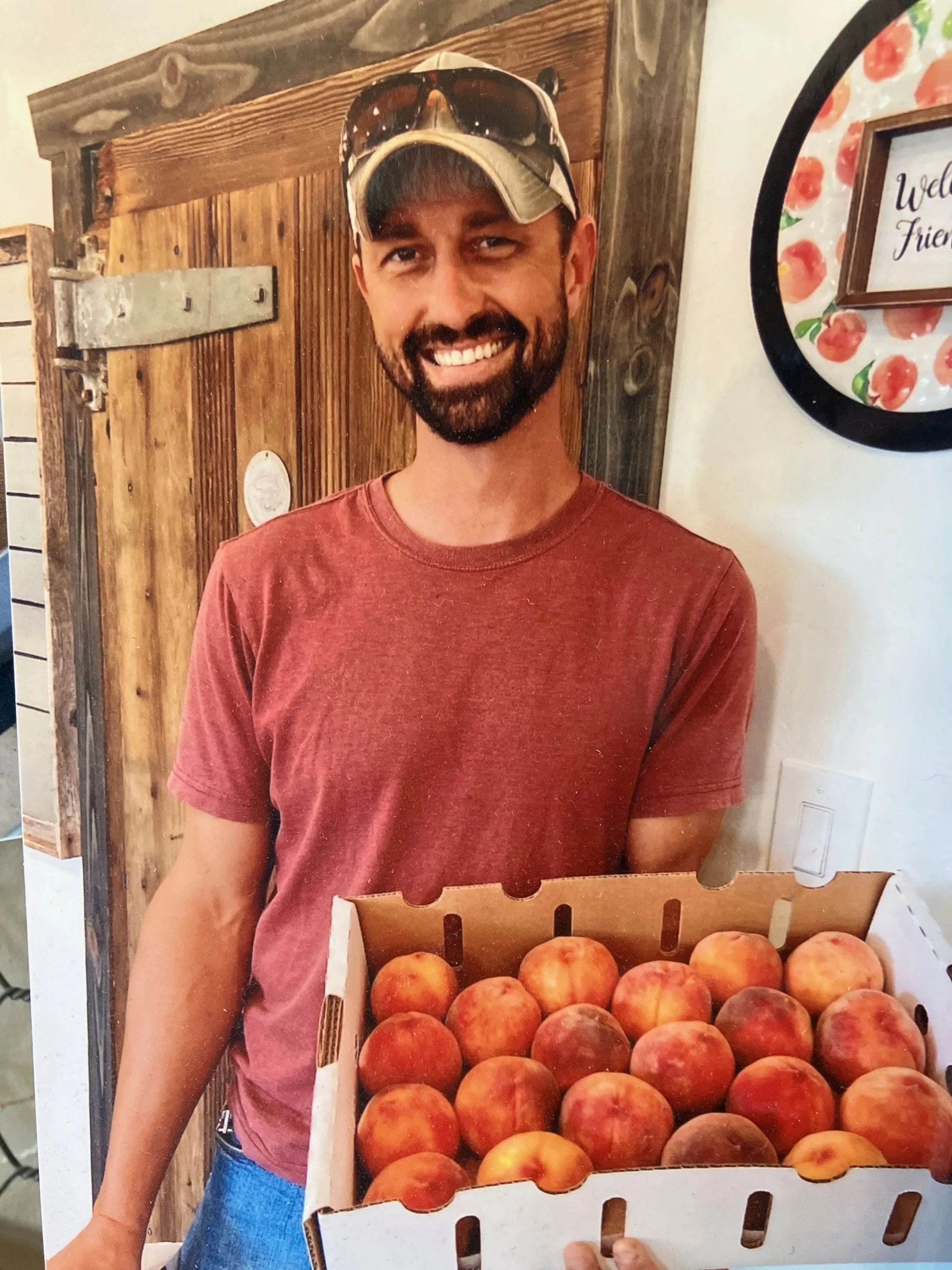 A man smiling with a box of peaches