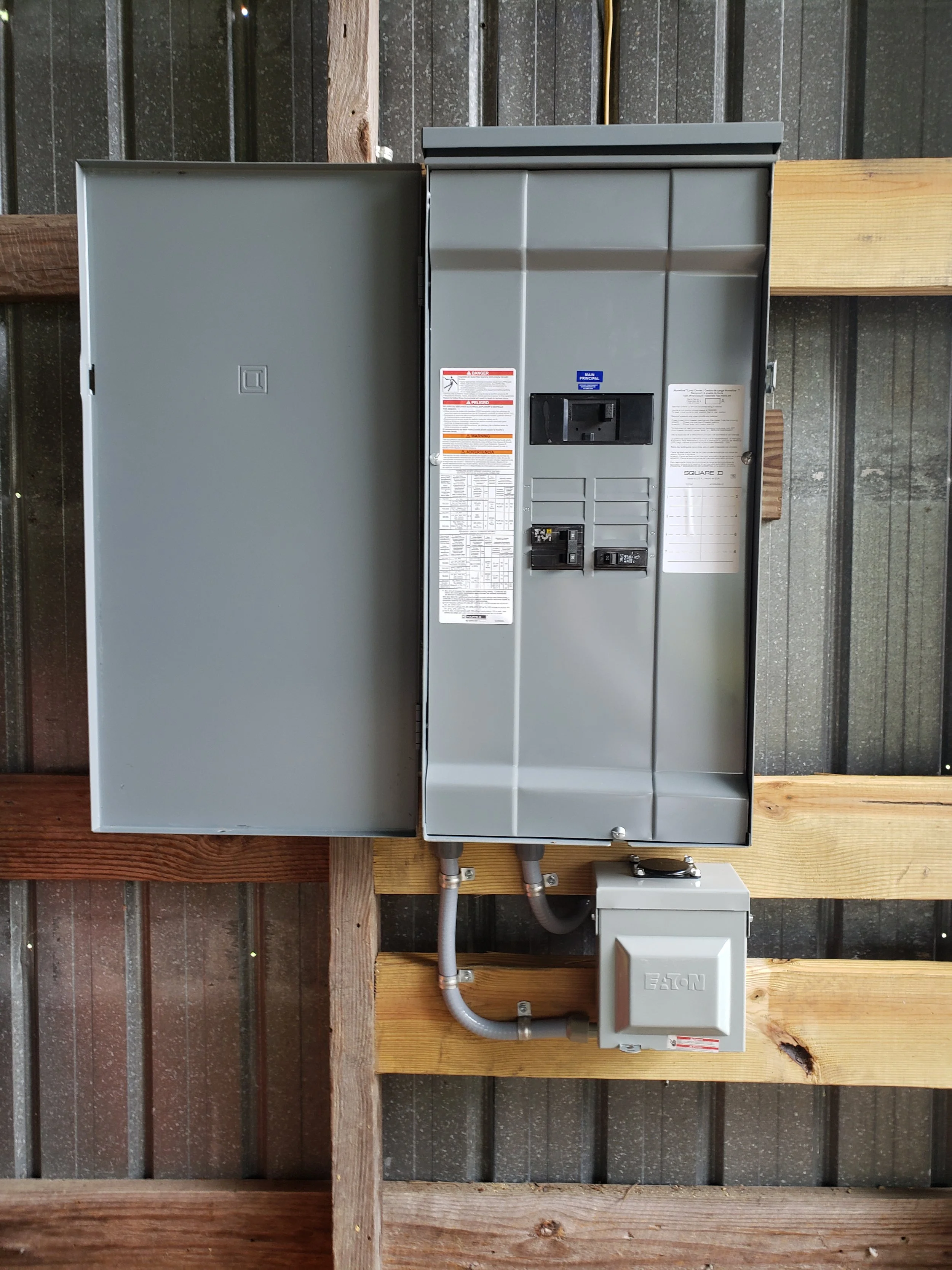 Electrical breaker box mounted on a wooden and metal wall.