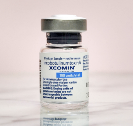 Vaccine vial labeled XEOMIN for injection, containing 100 units per vial, on a light background.