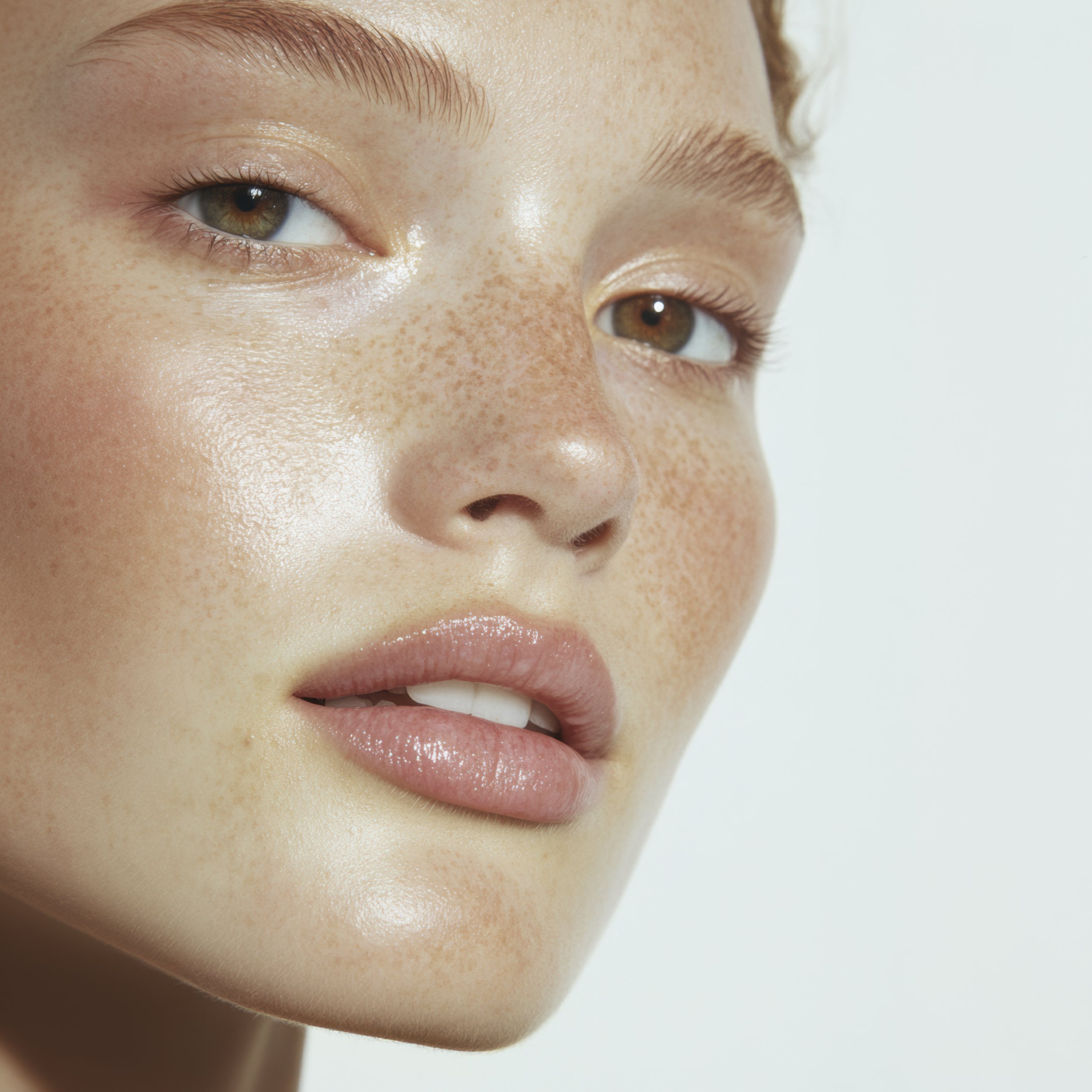 Close-up of a young person with light skin, brown eyes, freckles, and pink lips.