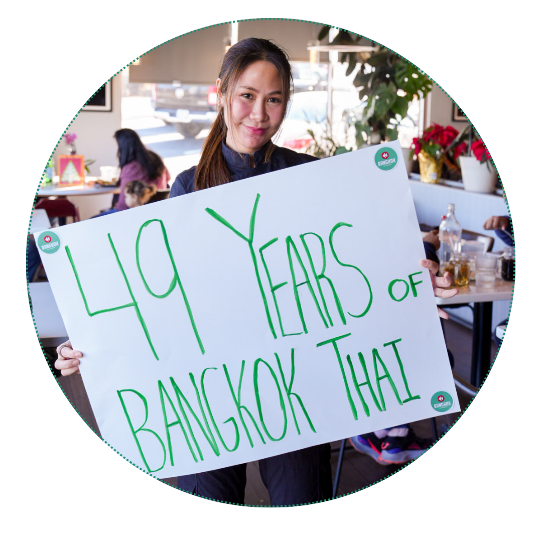 Chef pattie Lawlertratana holding a sign that says 49 years of Bangkok Thai
