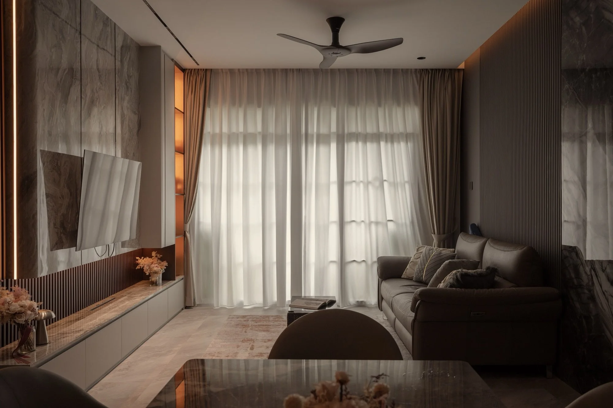 Quiet luxury, expressed through layers of texture.
A refined living and dining space where bold marble veining meets the warmth of dark timber, creating a balance between statement details and understated elegance.
Fluted wall panels introduce rhythm