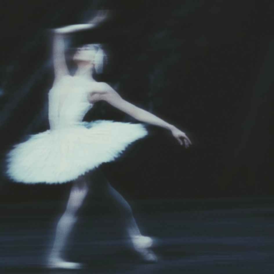 A ballet dancer in a white tutu practicing on stage.