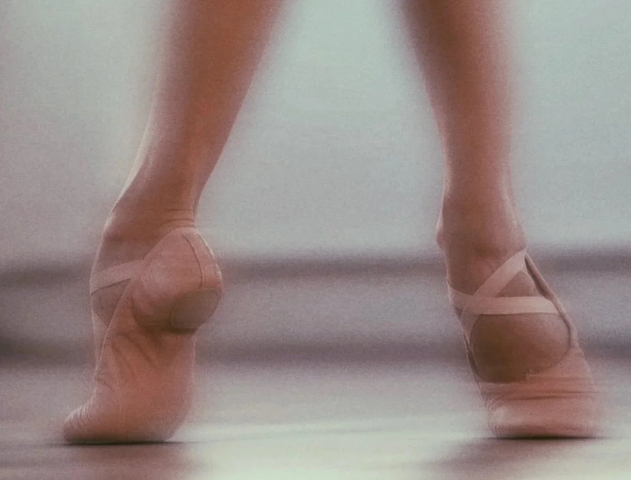 Close-up of ballet dancer's legs and feet in pointe shoes, standing on tiptoe.
