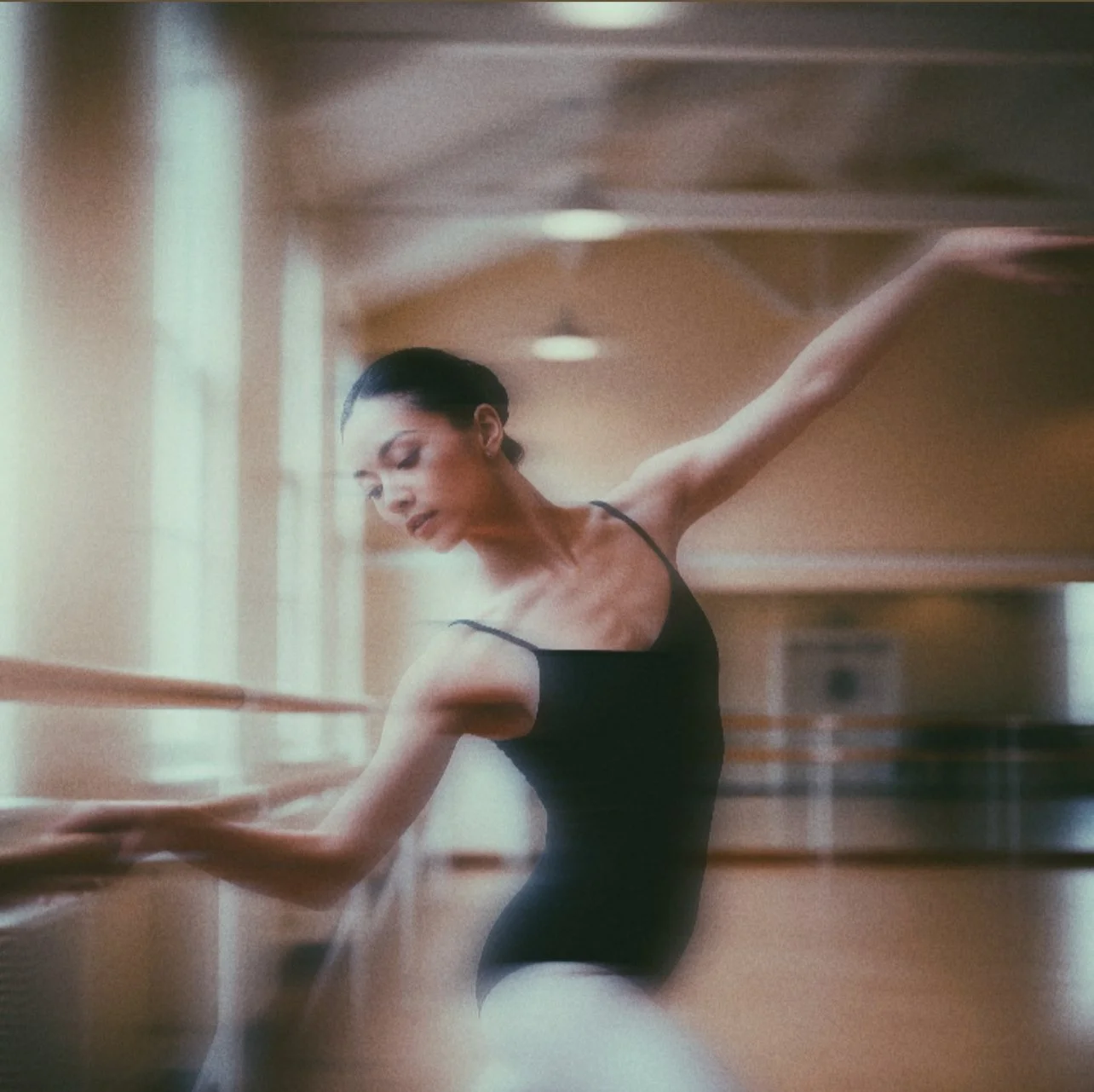 Ballet dancer practicing at the barre in a dance studio.