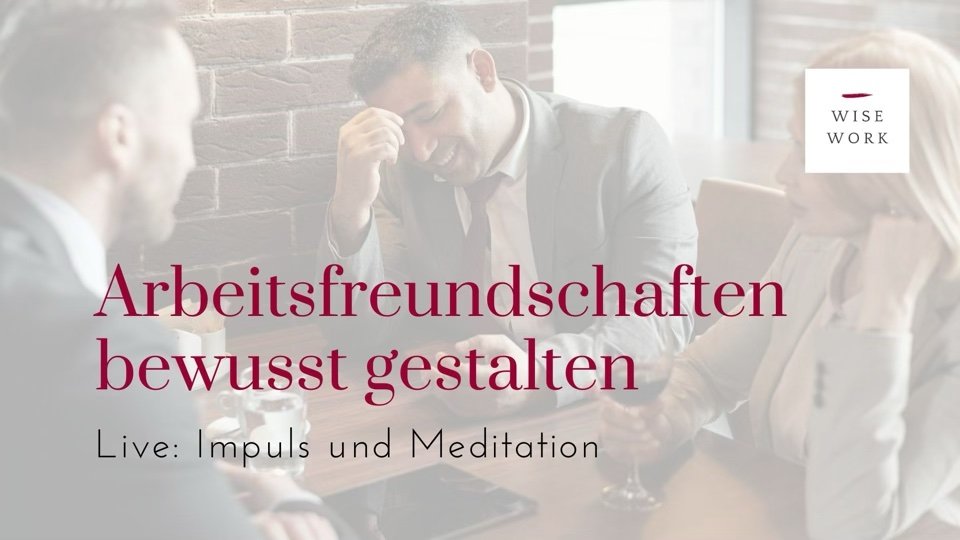 Freunde bei der Arbeit sitzen um einen Tisch und lachen.