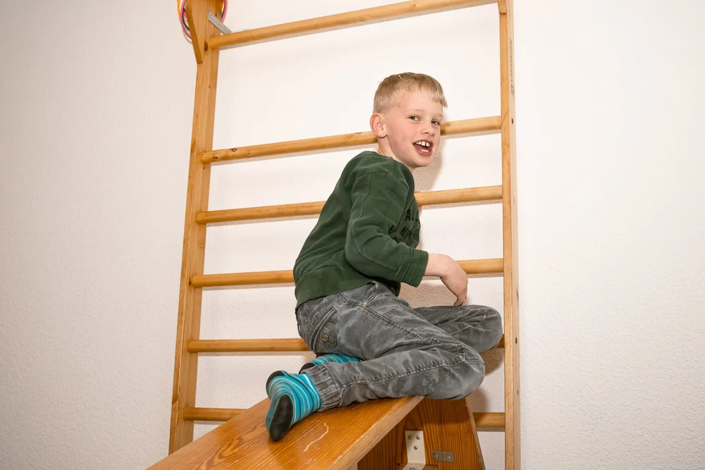Lachender Junge auf der Sprossenwand