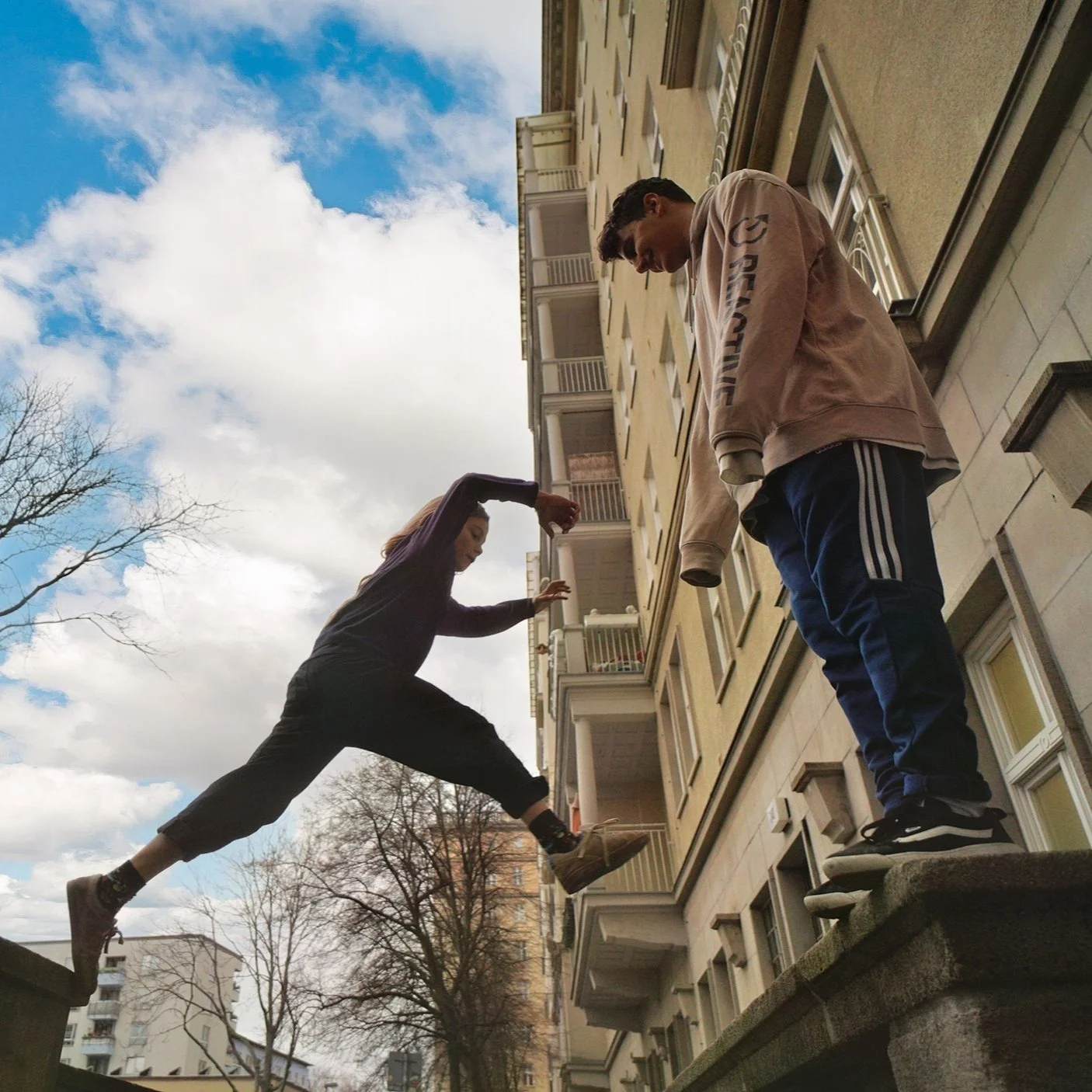 Ein Kind an einer Mauer in Berlin, daneben der Trainer