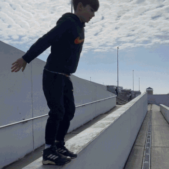 Kinder trainieren bodennah an einer niedrigen Mauer in Berlin