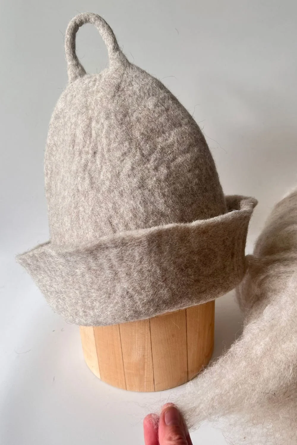 Wool sauna hat on a wooden head form, showing the space above the crown