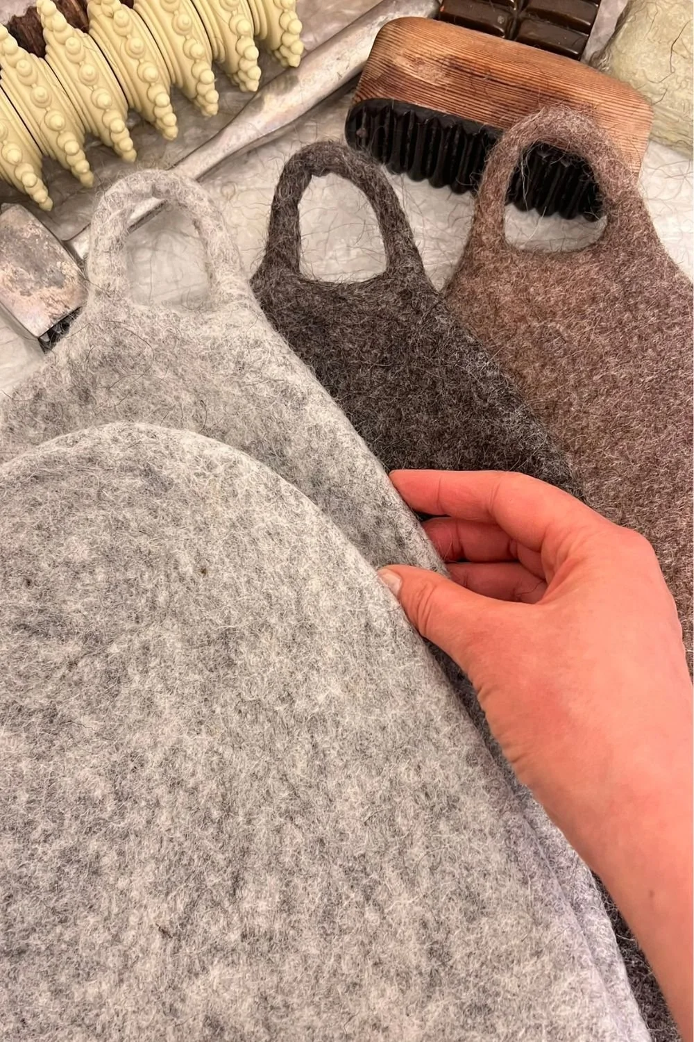 Artisan hand-finishing a handmade undyed wool sauna hat with traditional wooden felting tools, made in Europe FELTFORMA