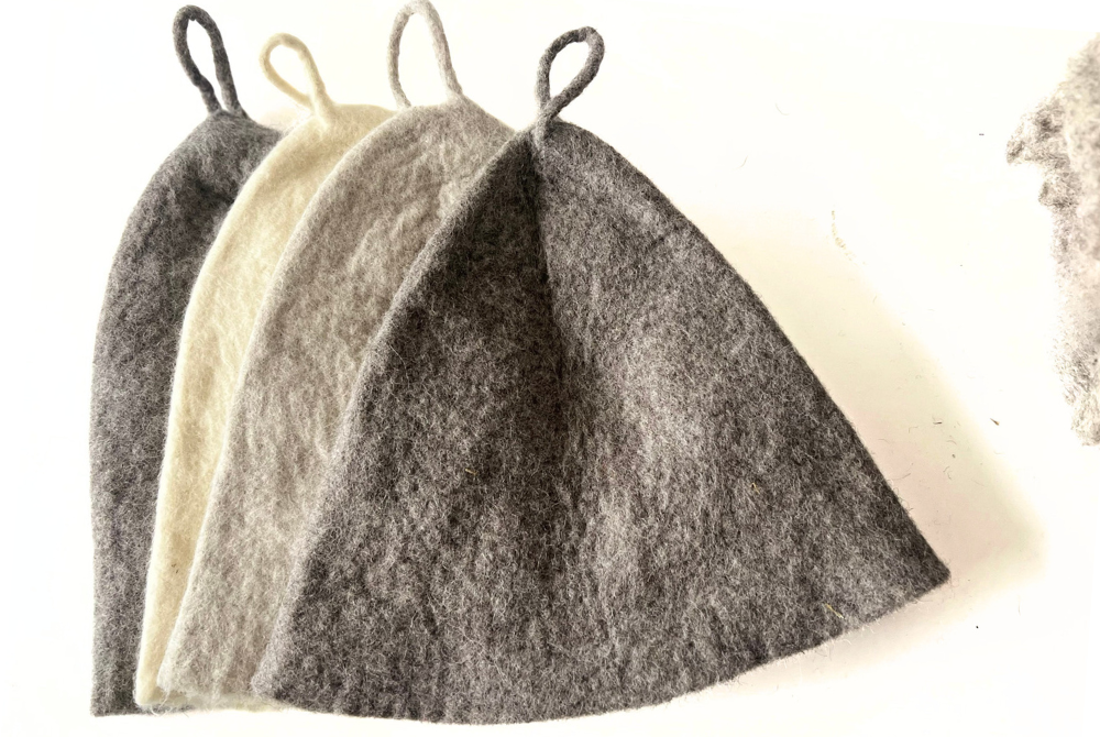 Four undyed wool sauna hats fanned out in charcoal, cream, light gray and dark gray, each with a wool loop
