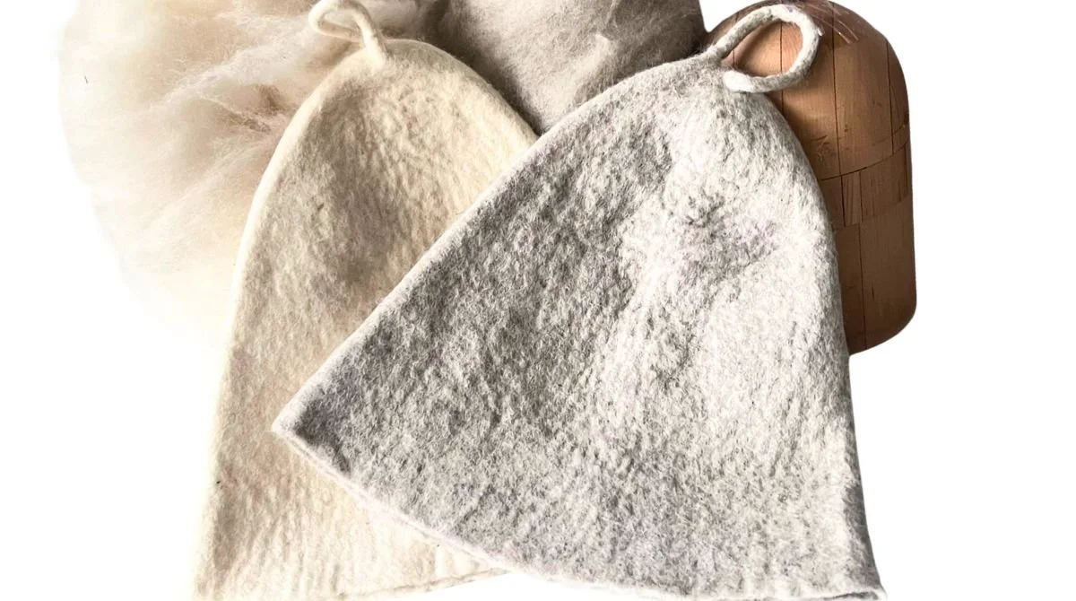 Handmade undyed wool sauna hats in natural cream and grey with raw Tyrolean mountain fleece — mulesing-free, water-washed only, no dyes, no chemicals. Hand-sculpted by Feltforma in Vilnius, Lithuania.
