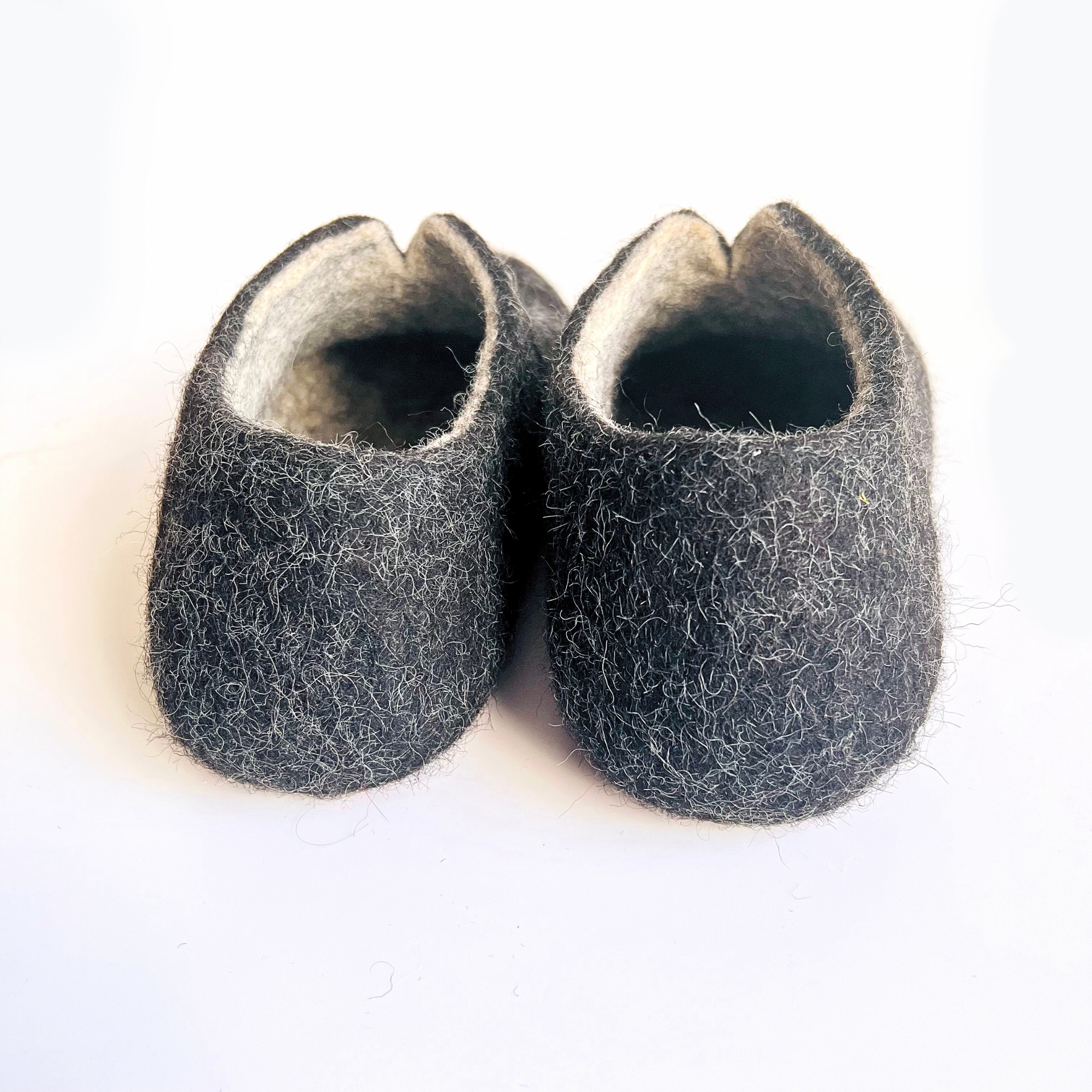 Women’s wool slippers with wide fit, handmade in charcoal felt with natural eco soles. Designed to solve problems of tight shoes, they bring breathable ease and mindful style.