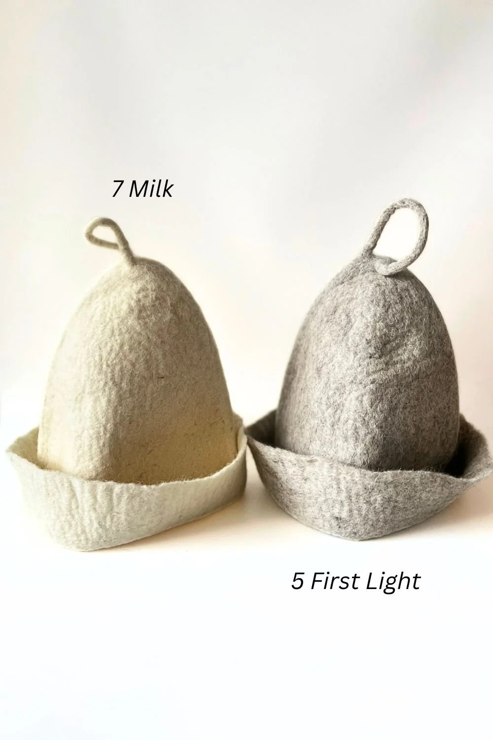 Two undyed wool sauna hats, one white (Milk) and one light gray (First Light), hand-sculpted by FELTFORMA