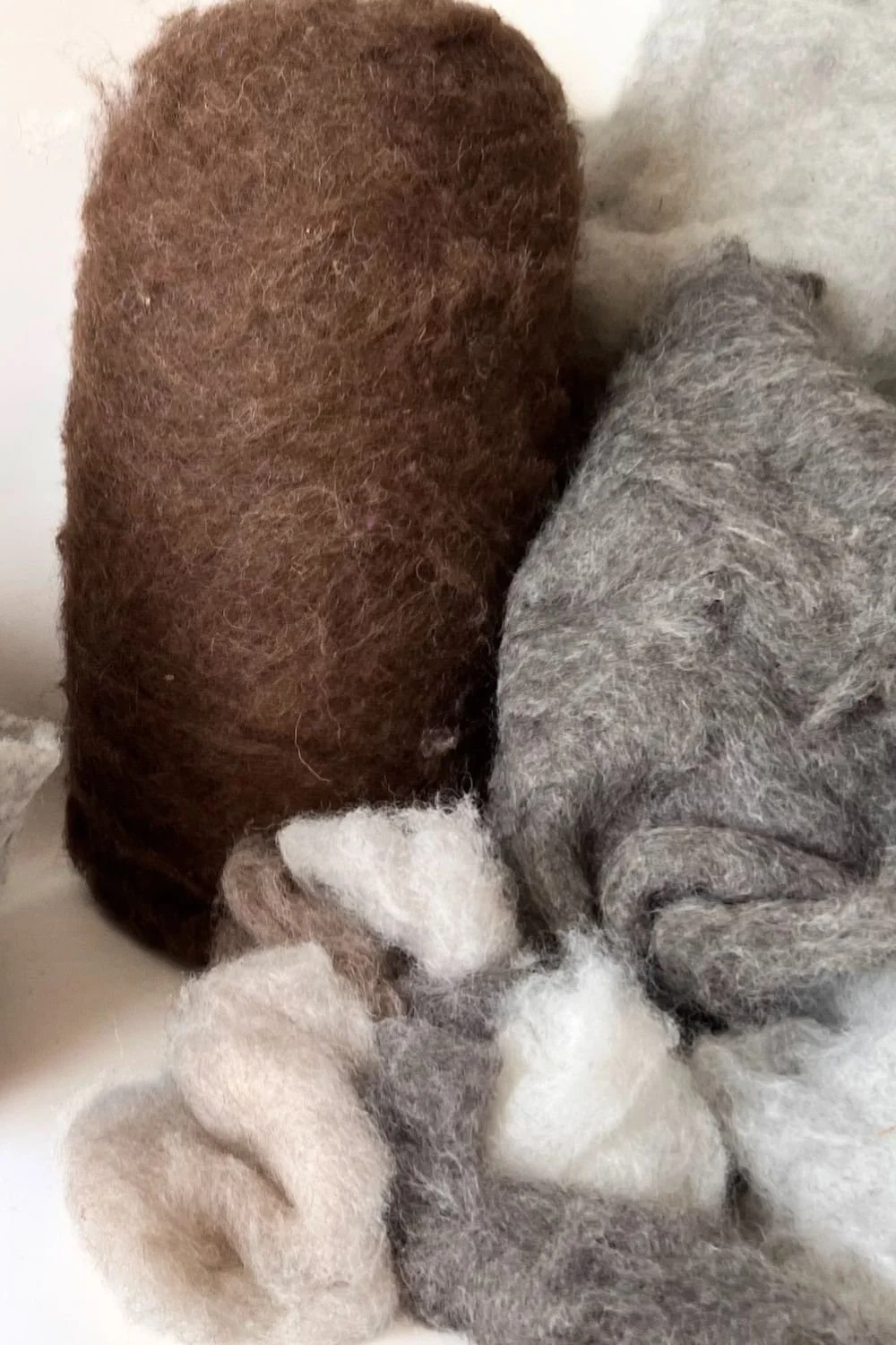 Raw undyed wool fiber in natural colors, the material behind Feltforma's handmade sauna and cold plunge hats