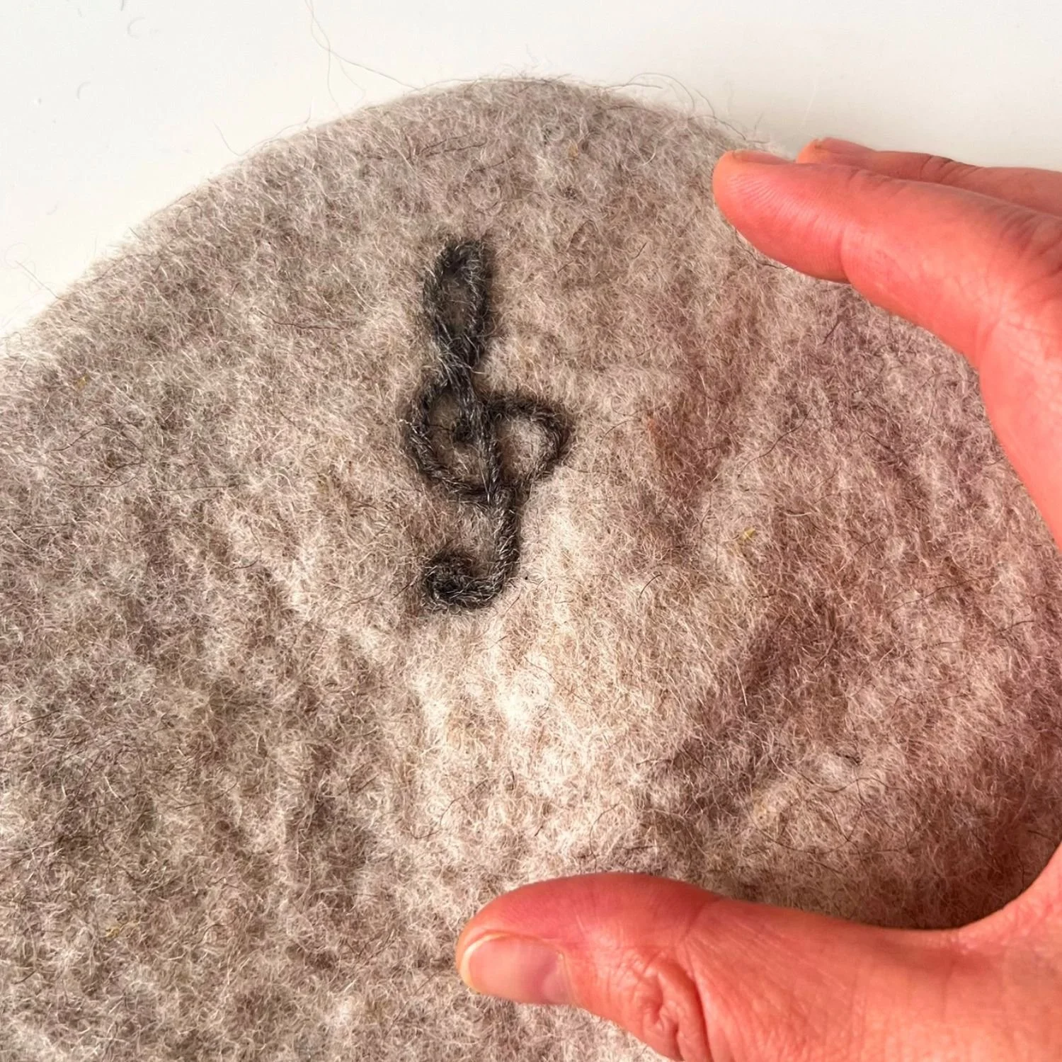 Close-up of a needle felted symbol worked into a wool sauna hat, felted into the fiber, not glued or stitched