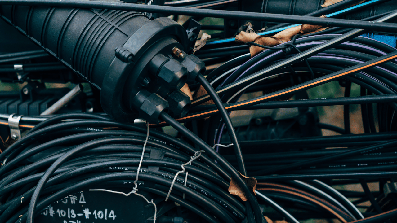 Close-up of an electrical equipment box with multiple black cables and wires connected, some secured with twist ties, and a large black flexible conduit.