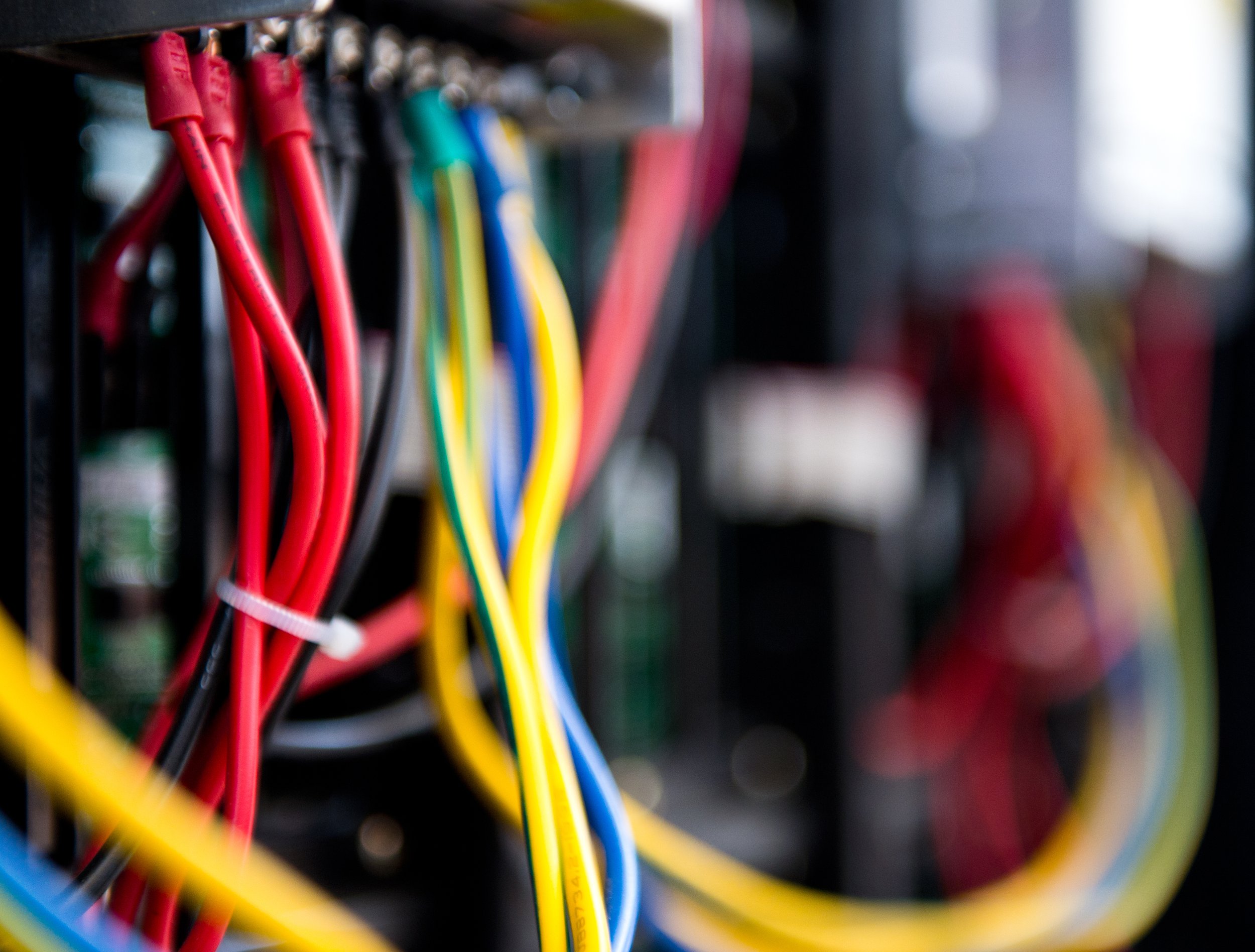 Close-up of multicolored electrical wires connected to a circuit board or electronic device.
