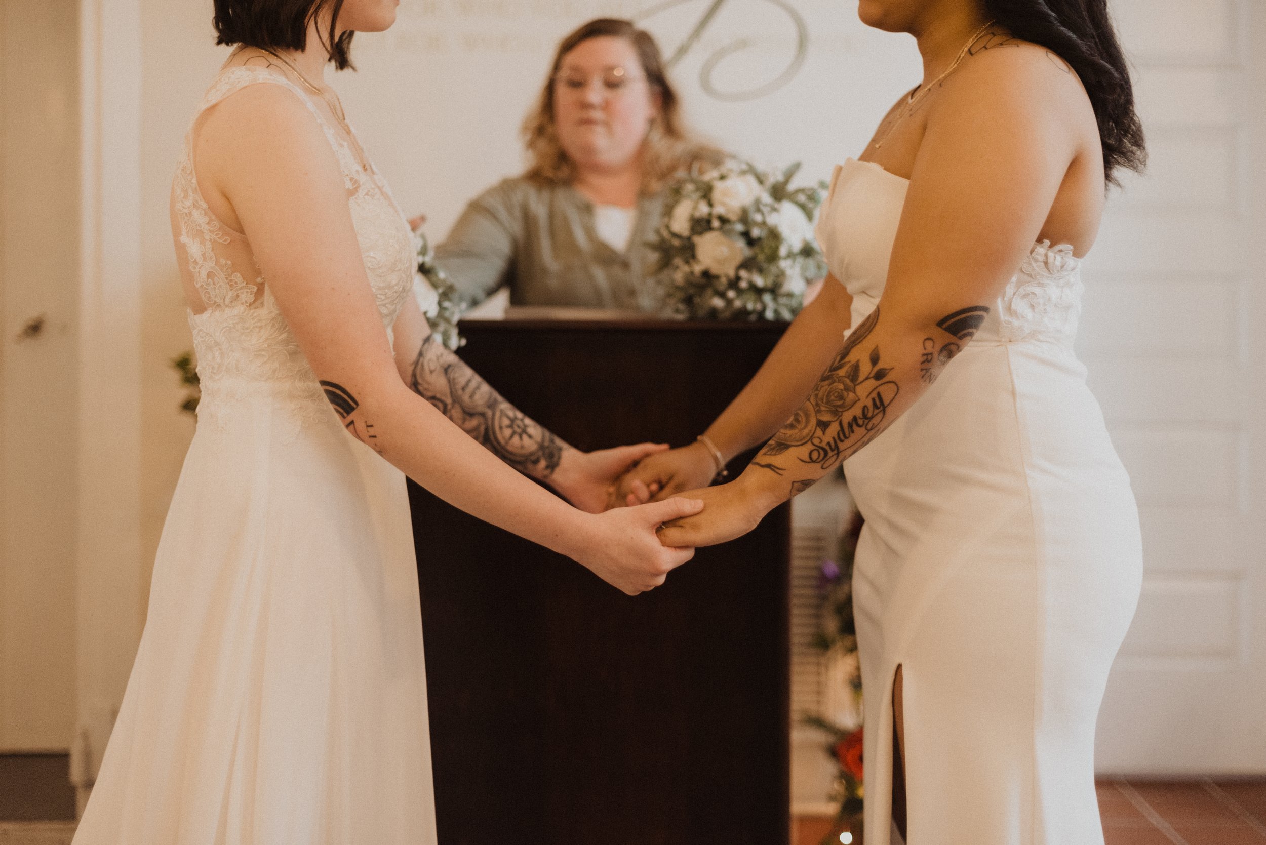two brides holding hands at the altar