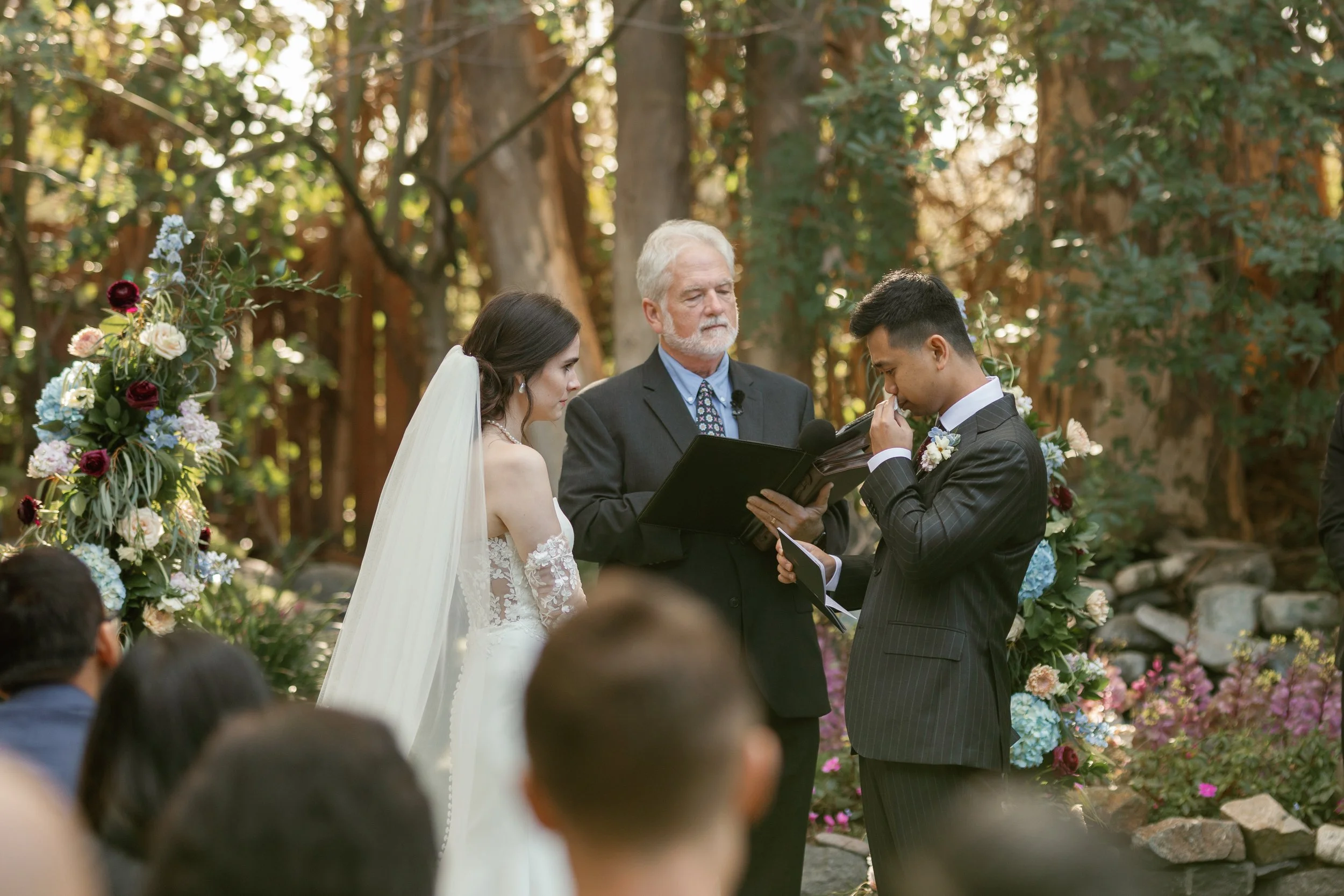 groom wiping his tears while reading wedding vows to bride at twin oaks wedding venue in san marcos, california