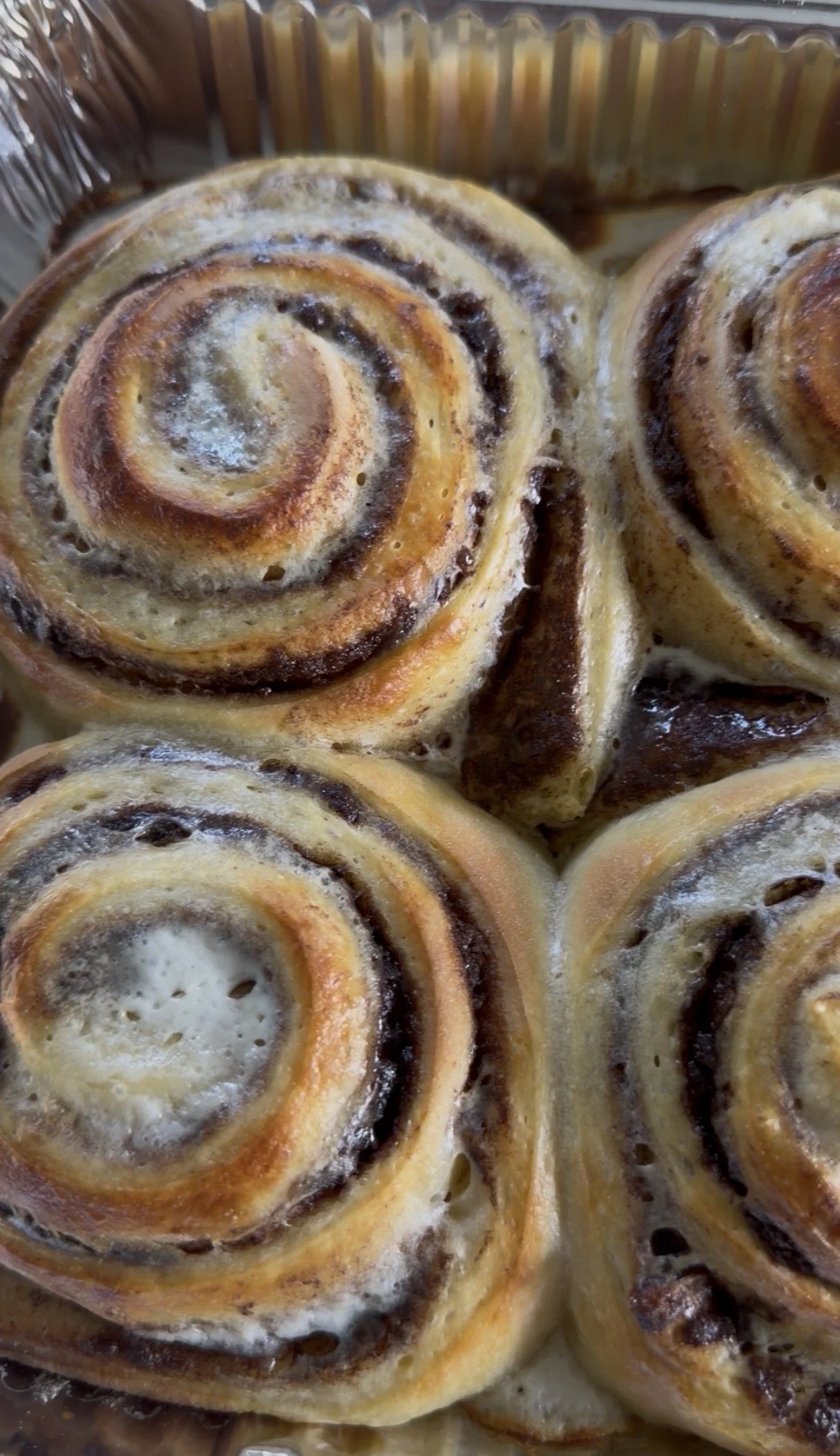 Close-up of freshly baked cinnamon rolls with swirled patterns and icing.