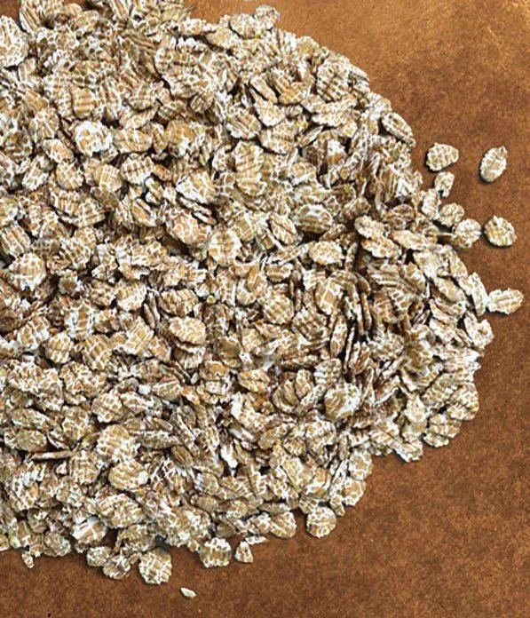 Pile of New York Craft Malt flaked oats on a wooden surface