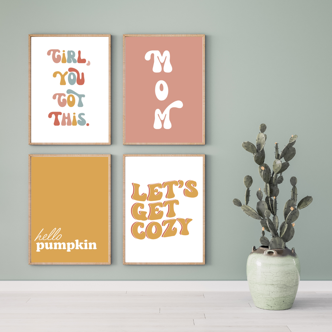 Four framed posters with motivational and seasonal quotes on a green wall, next to a large potted cactus. The quotes are: "Girl, You Got This," "Mom," "hello pumpkin," and "Let's Get Cozy."