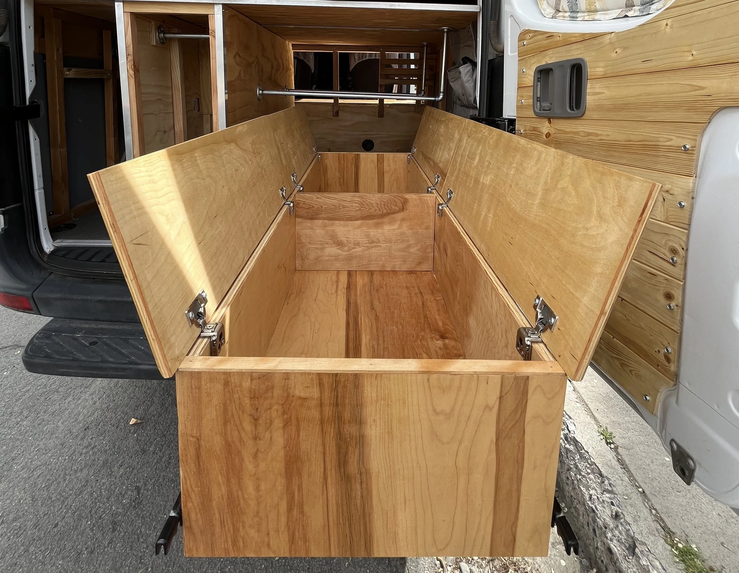Wooden storage compartments with open lids inside a vehicle.