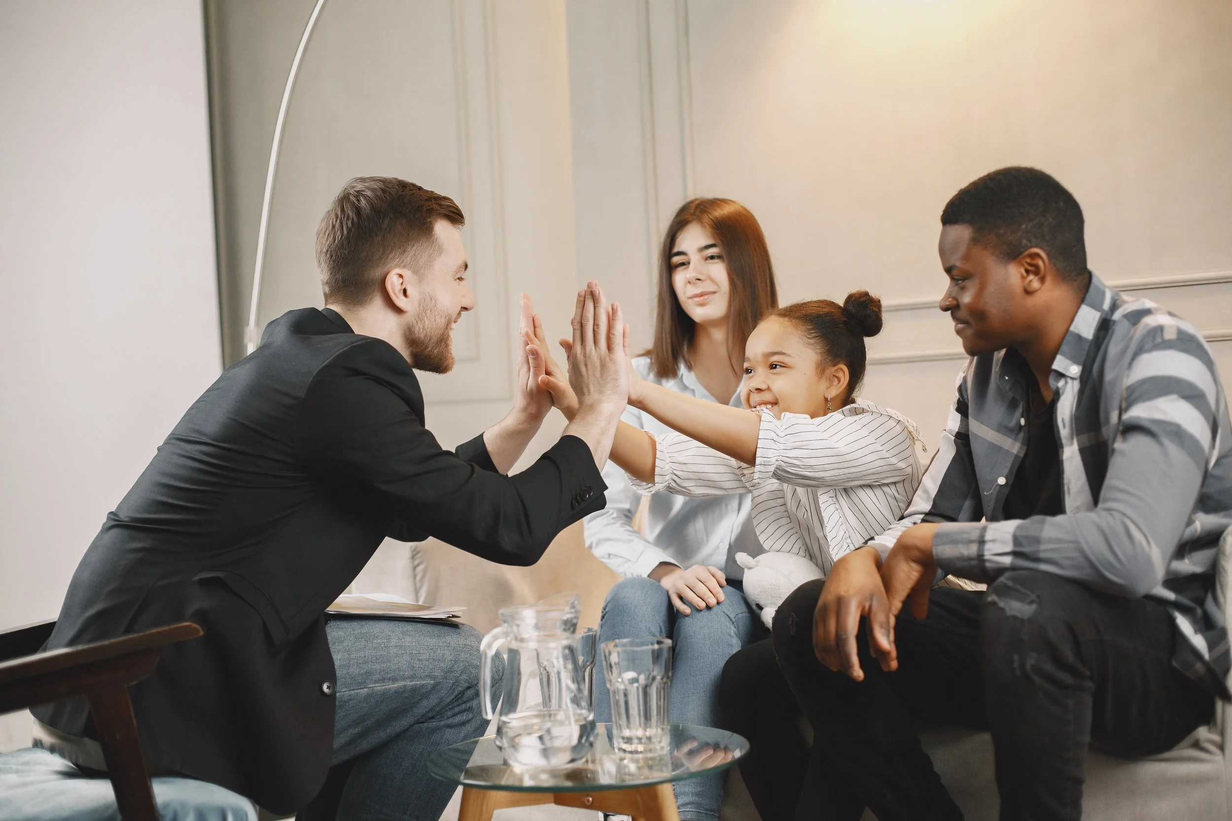 A family in family therapy high fiving their therapist
