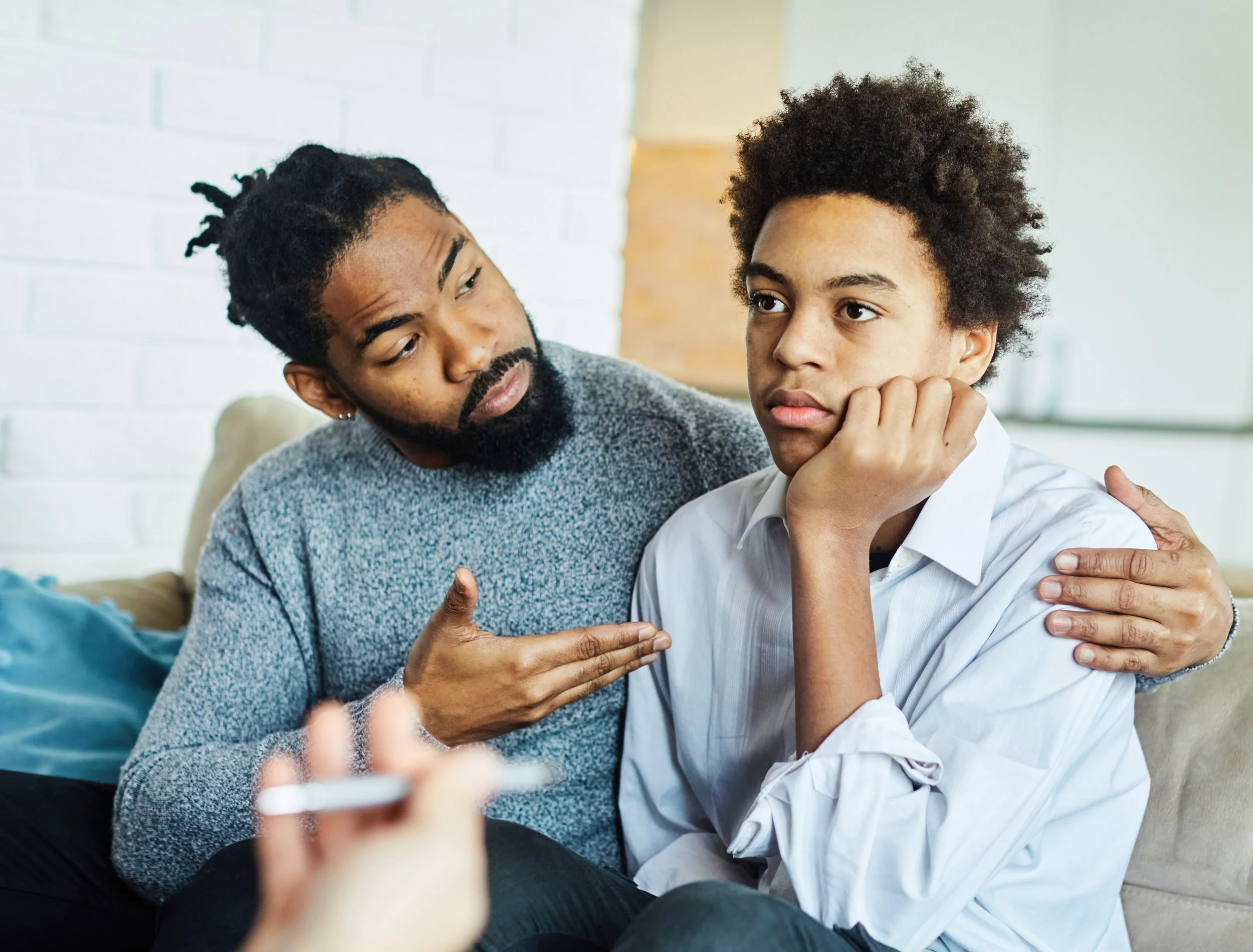 teen client being supported by his father in therapy