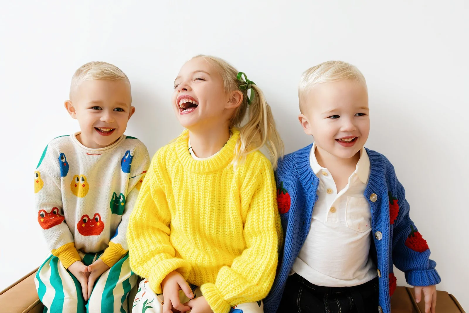 Studio portrait of three children sitting together against a white backdrop during a session at the Anderson Arts Building in Rochester, NY.