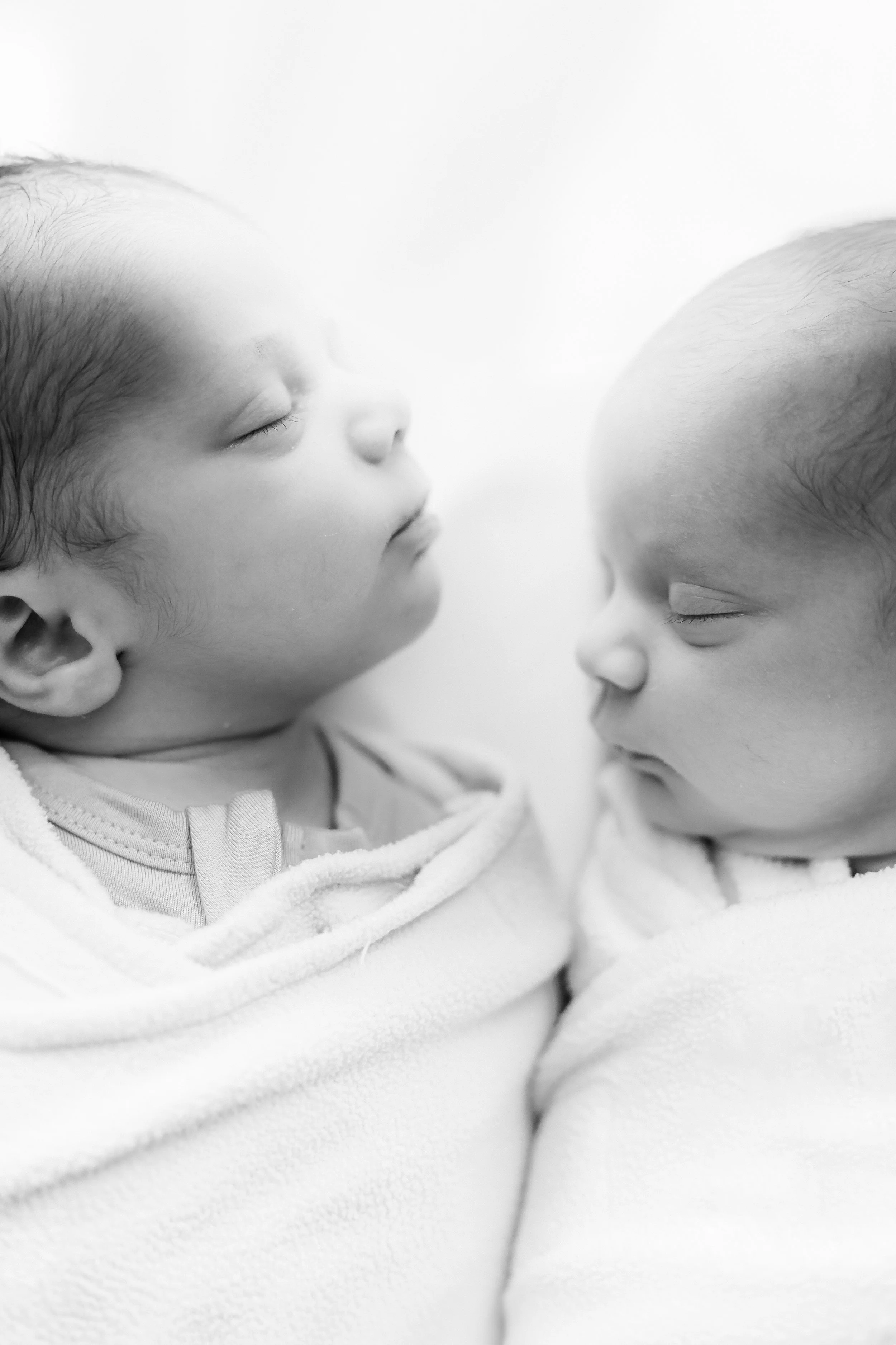 Black and white lifestyle newborn photo of twin babies resting together during an in-home session in Rochester, NY.