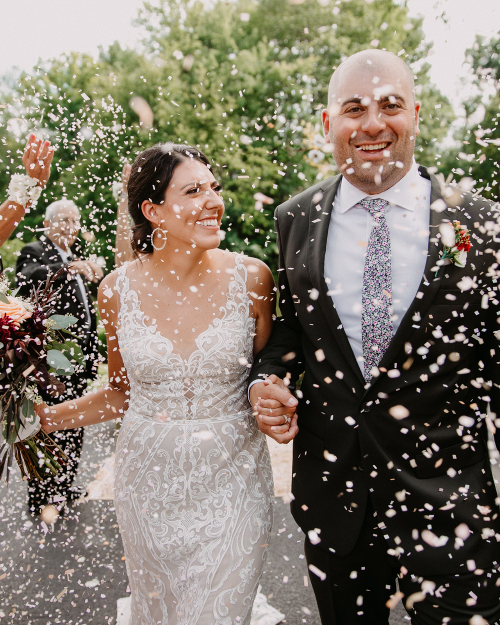 Bride and groom smiling and walking through confetti at their intimate outdoor wedding in Rochester, NY.