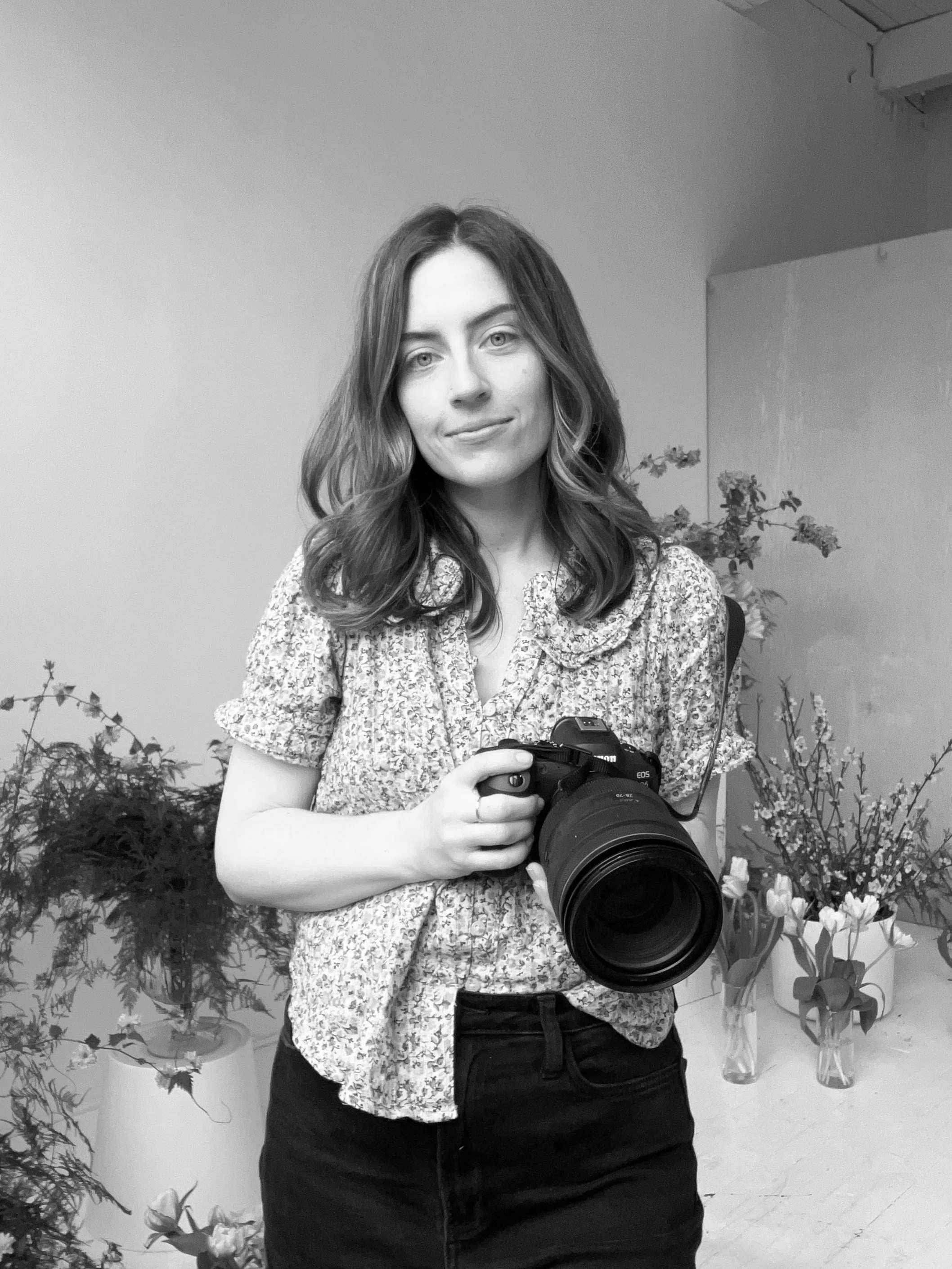 Lindsay Stephany, a Rochester, NY photographer, holds a professional camera and takes a selfie in her Anderson Arts Building studio.