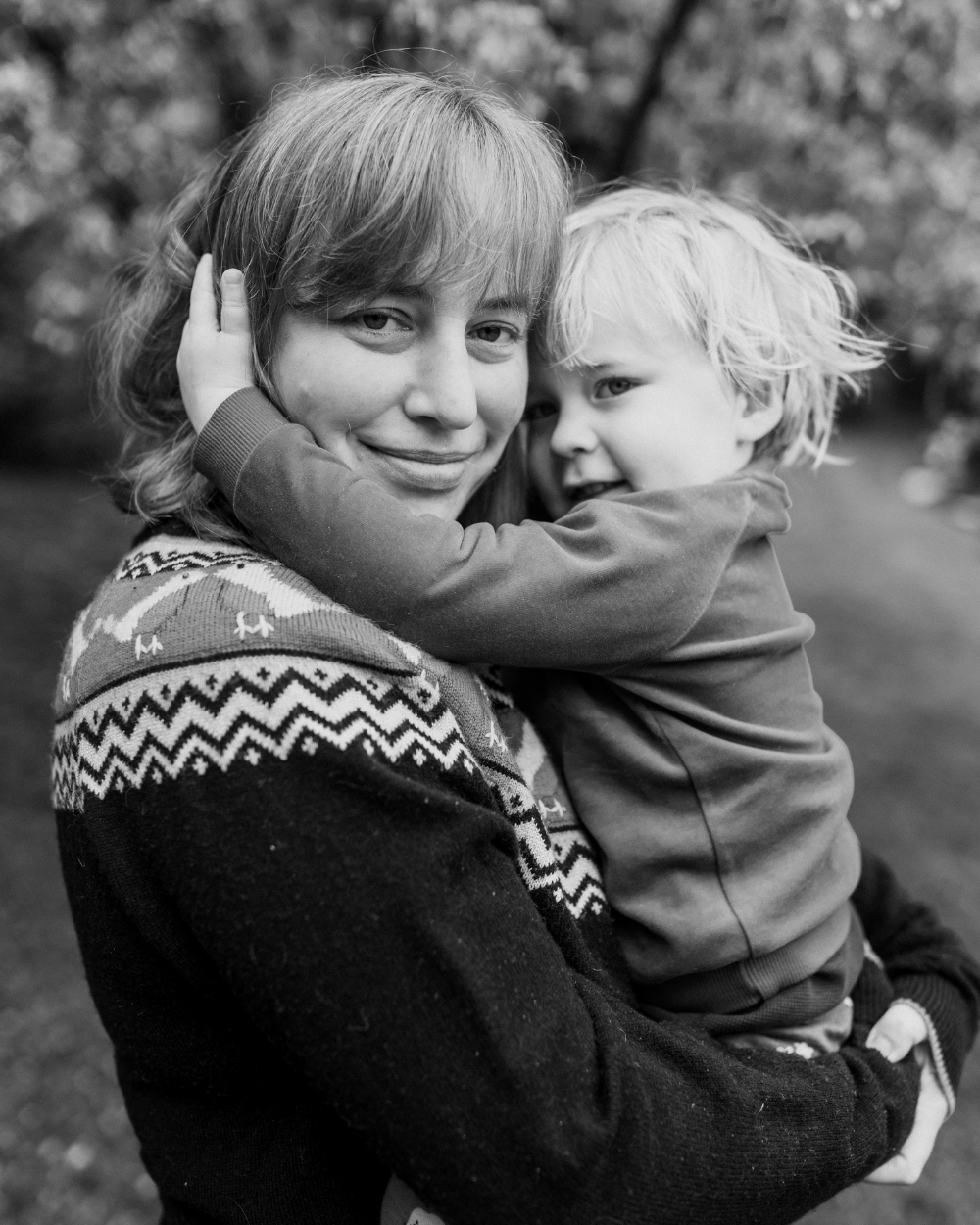 Candid family photo of a mother holding her young son during an outdoor mother’s day mini session in Rochester, NY.