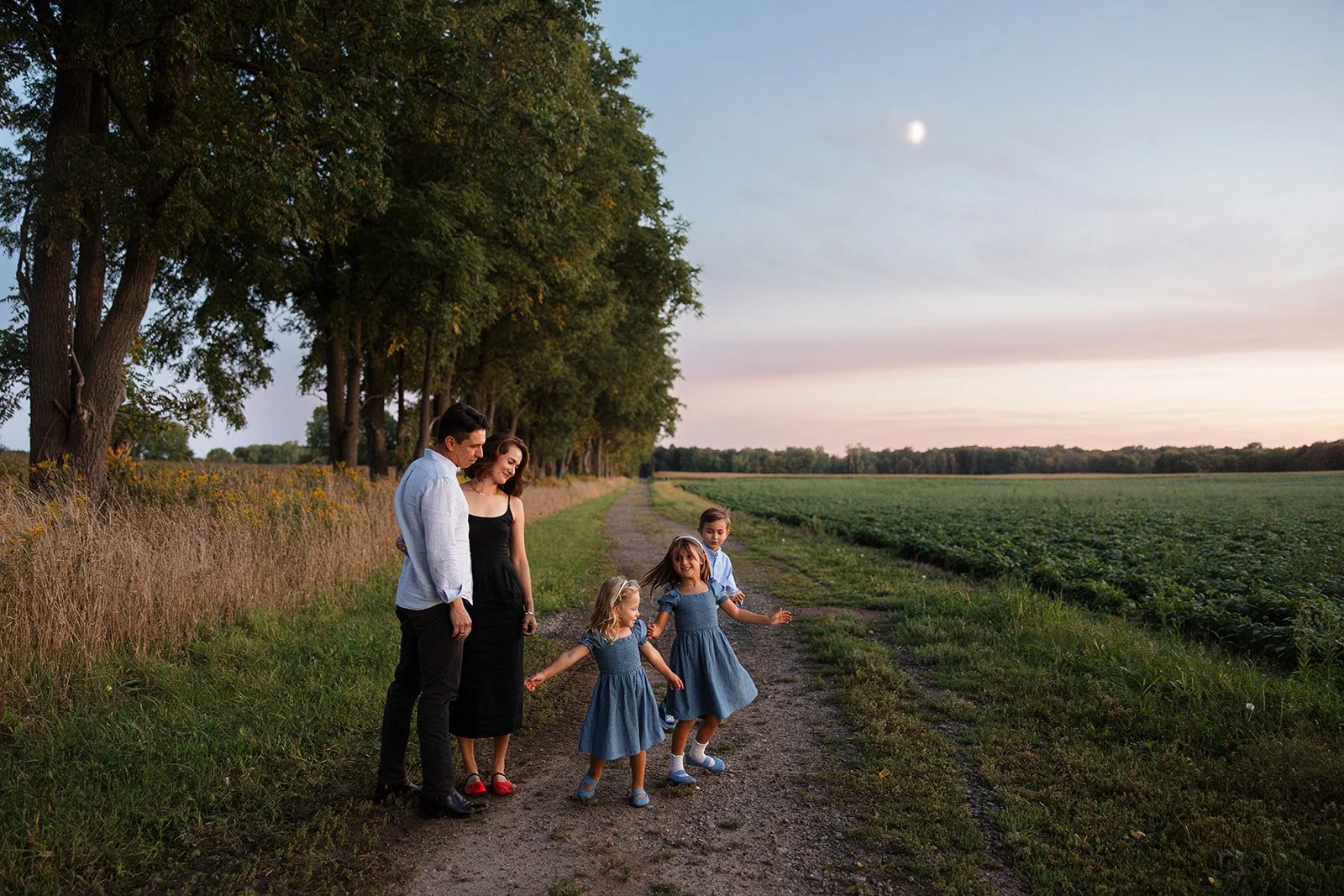 Family photo during a Flower Session at Flowerwell, showing a family of five playing in the moonlight next to a flower field in Rochester, NY.