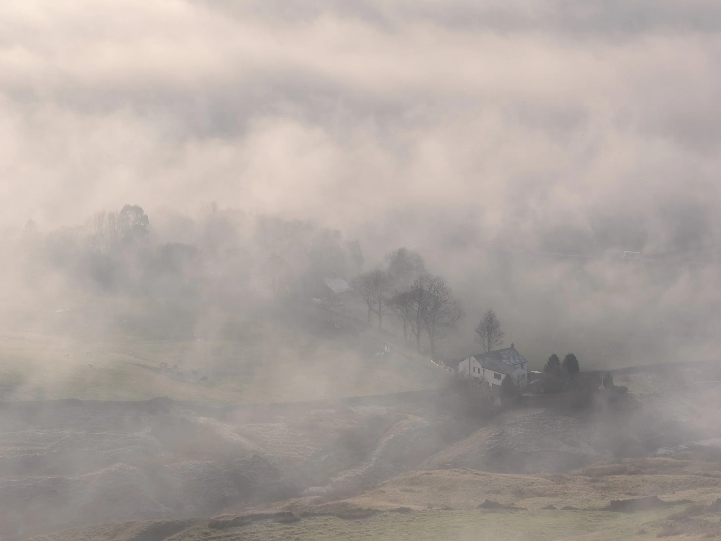 Newgate Farm in Newgate Valley, Rossendale, isolated and half-hidden by swirling morning fog with light filtering through the mist.
