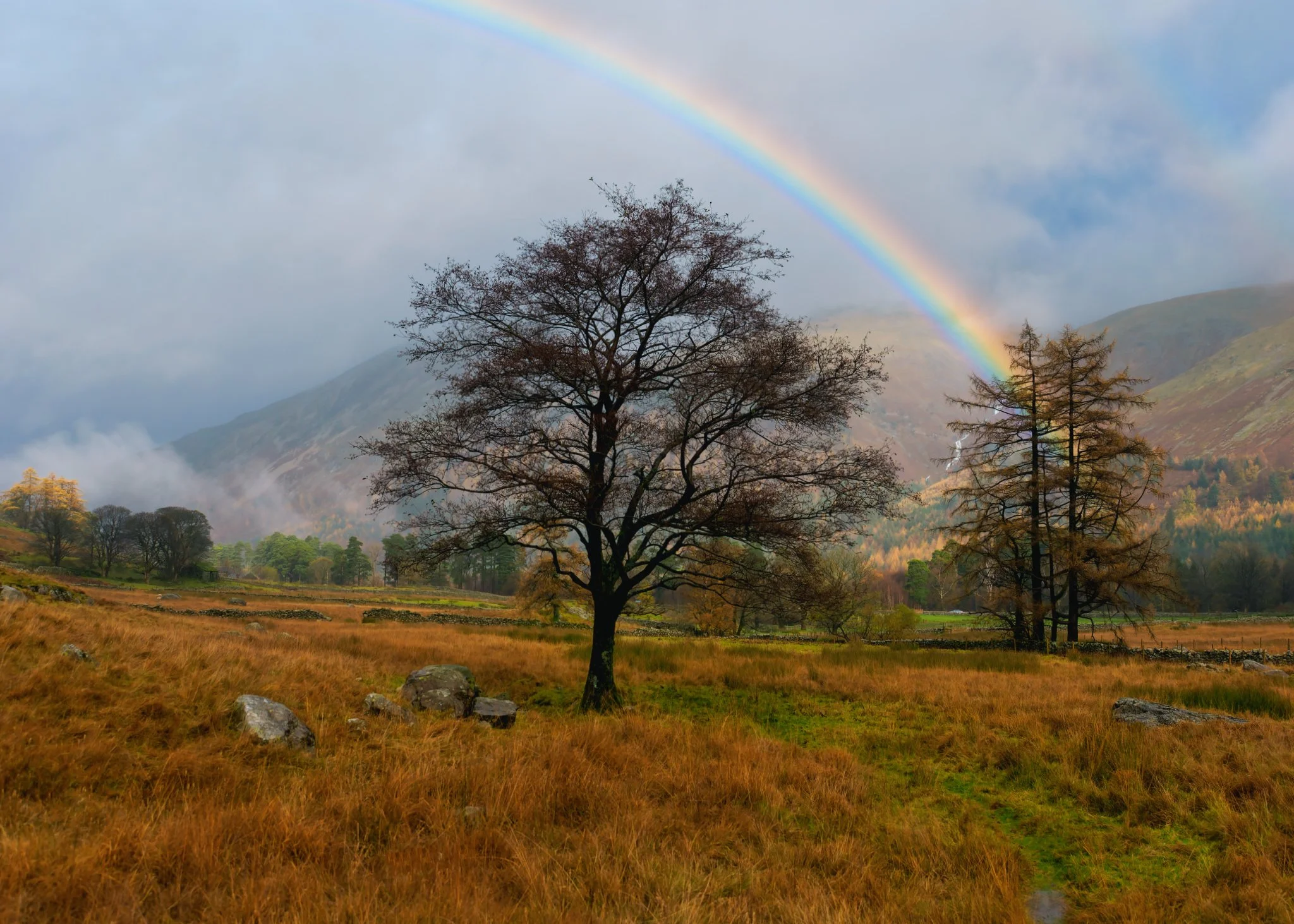 The Lake District’s dramatic upland terrain, with its craggy features, painted with light, emphasizing texture and depth, and completed with a breathtaking rainbow.