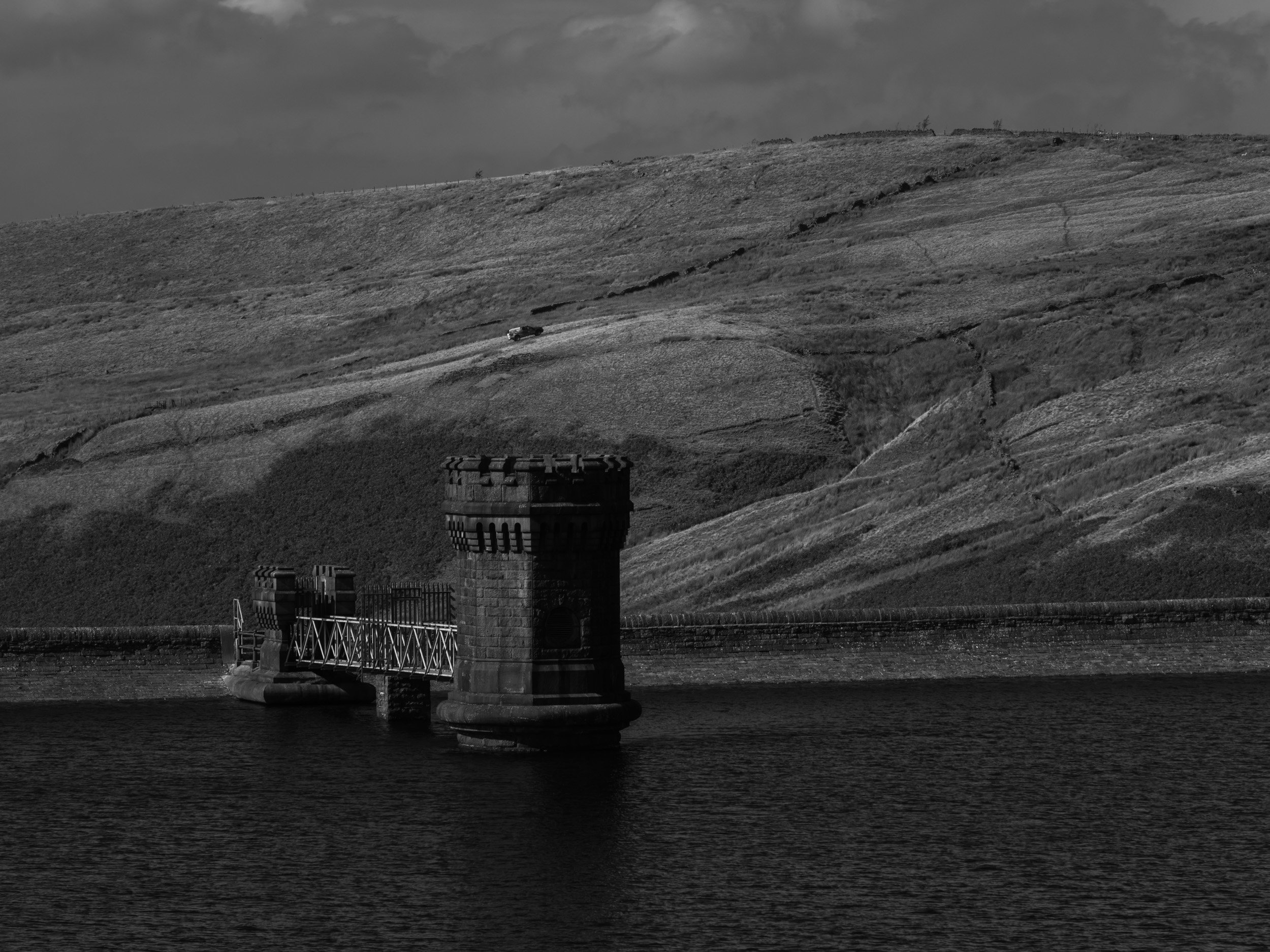 Black and white detailed photograph of the Victorian stone valve tower and footbridge at Scout Moor High Level Reservoir.