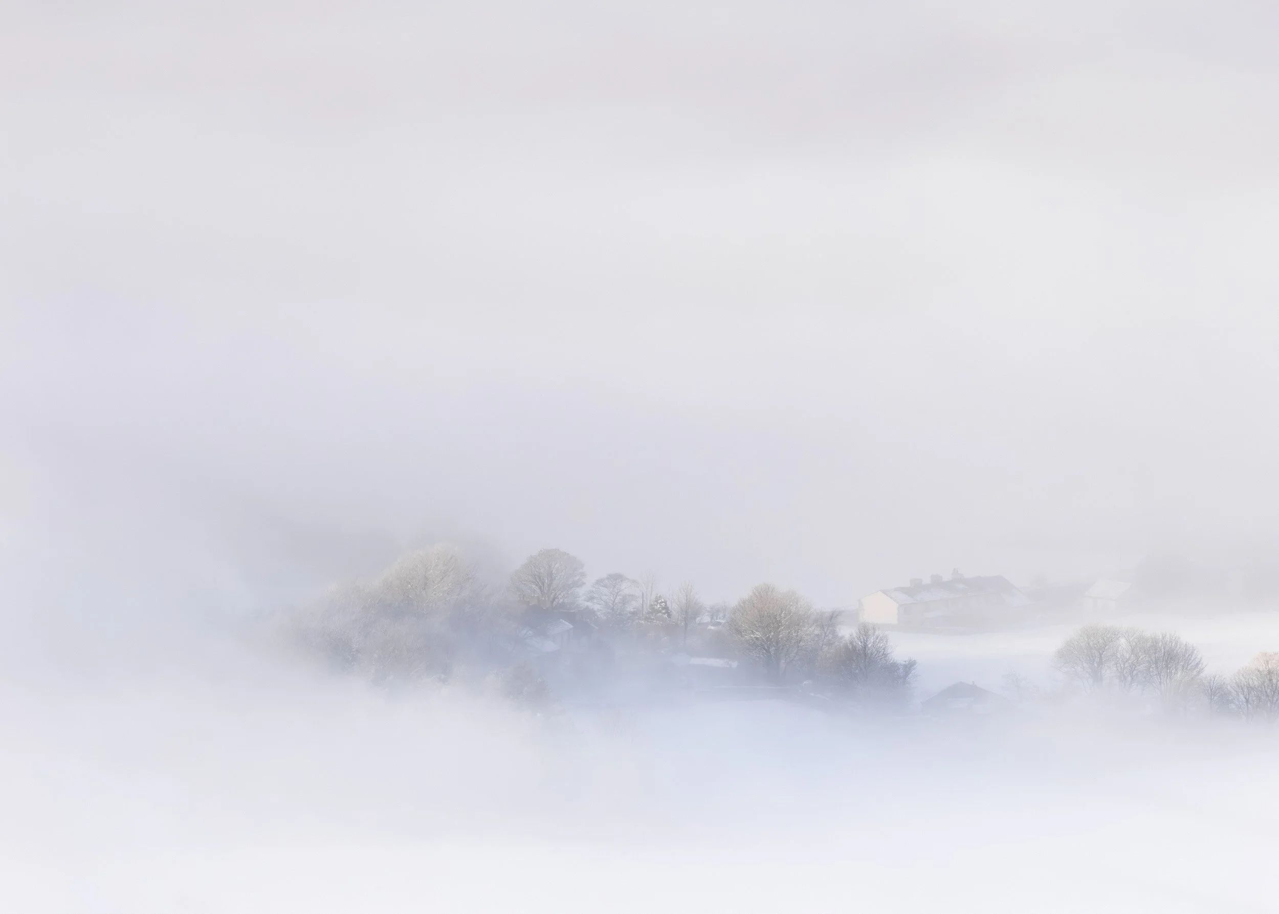 Ethereal view of Turn Village in Rossendale peeking through a thick sea of white fog, with frosted trees and faint stone houses.