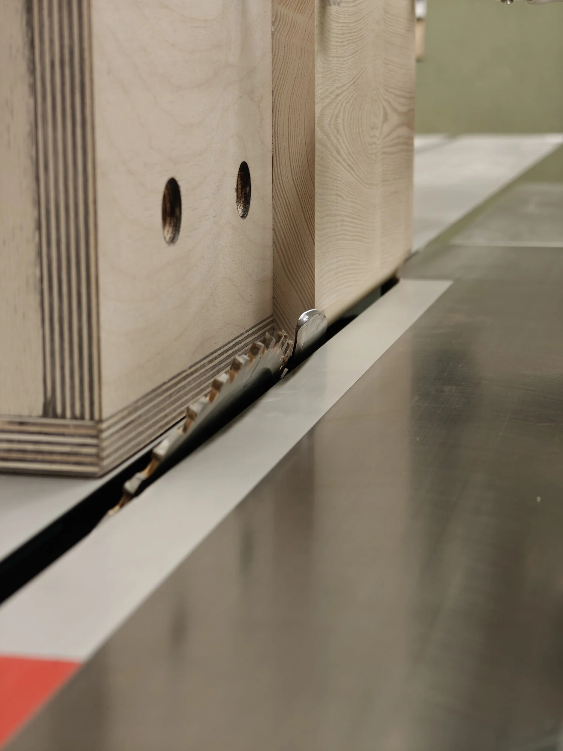 Close-up van een houtbewerkingmachine met houtblokken en een metalen geleider.