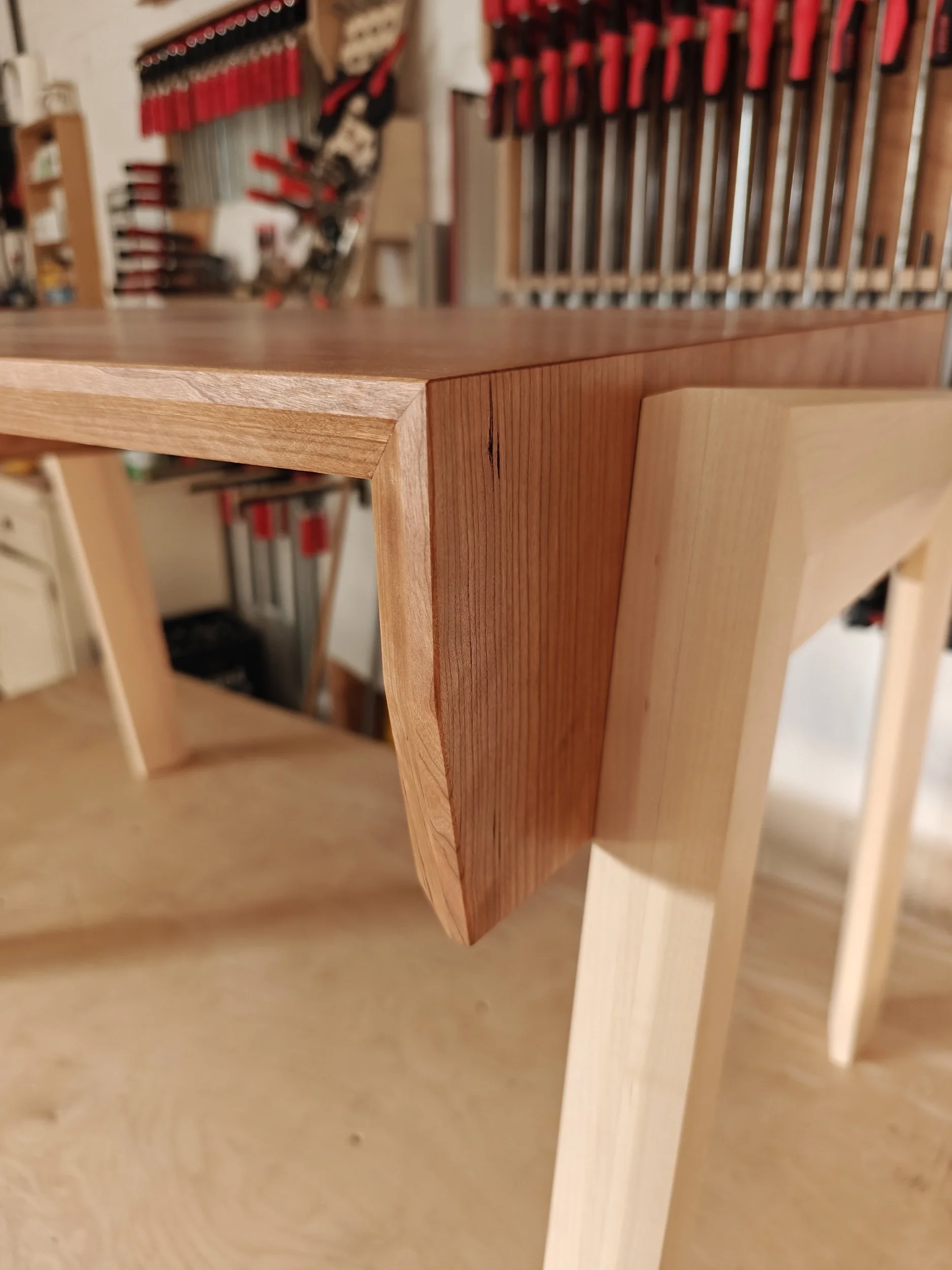 Close-up van een houten bureau met een hoekverbinding, gemaakt van esdoorn en kersenhout.