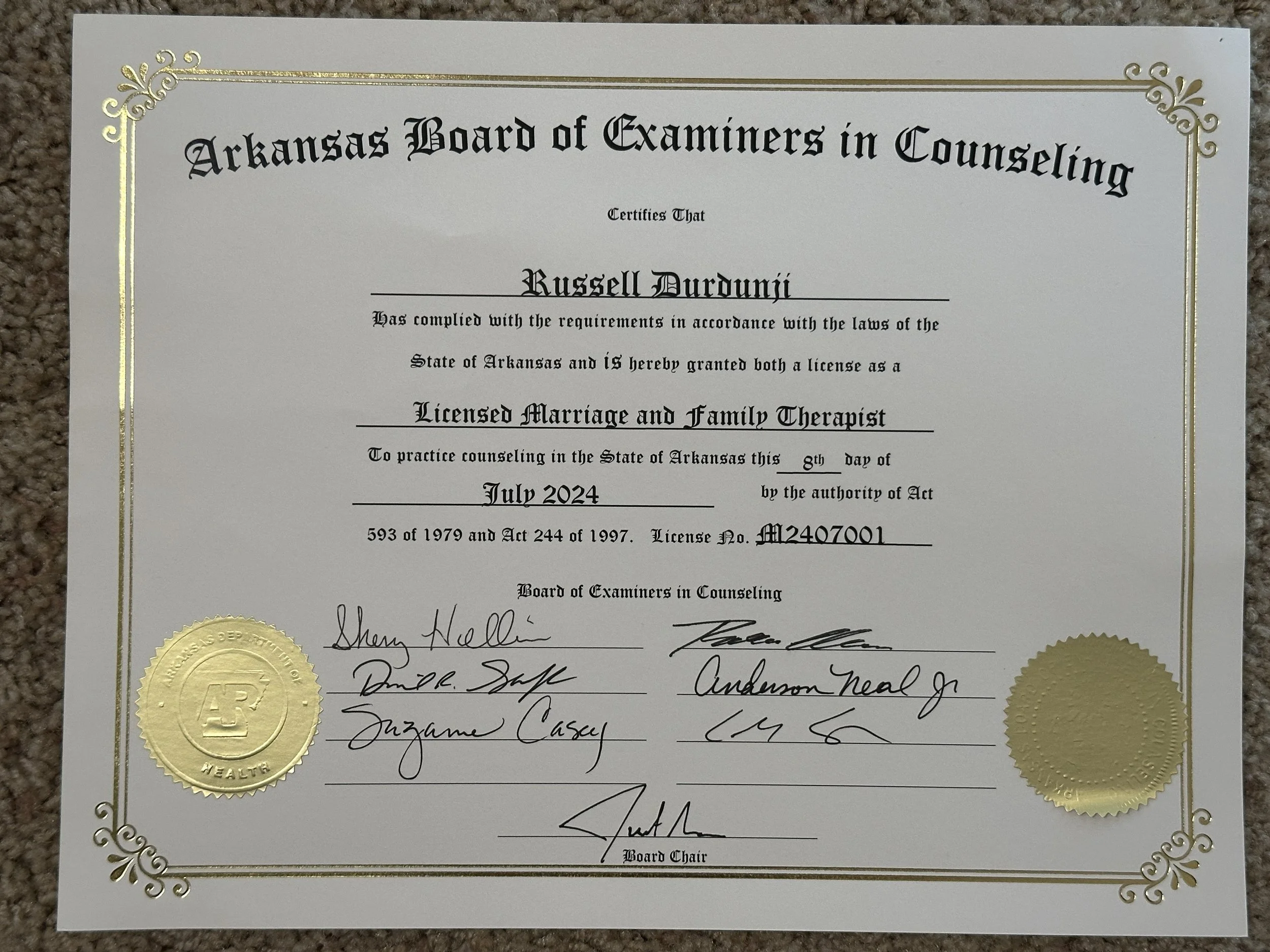 Official certificate from Arkansas Board of Examiners in Counseling, awarded to Russell Dourdunji, July 8th, 2024, with signatures and gold seals.