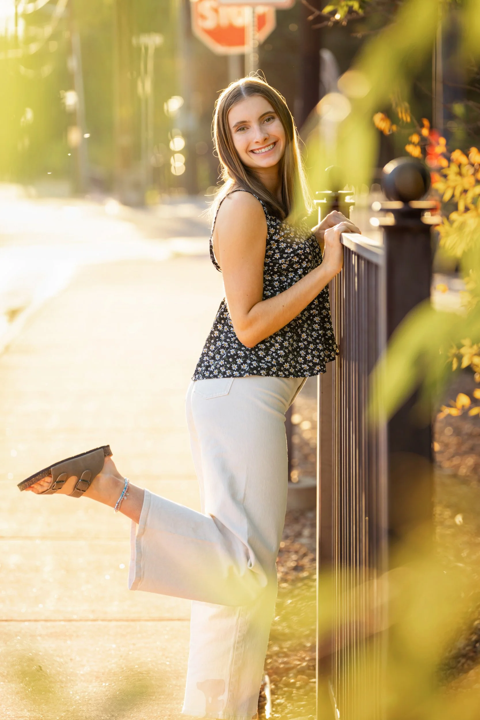 A high school senior girl poses through leaves in golden hour in downtown Buffalo, Wyoming.